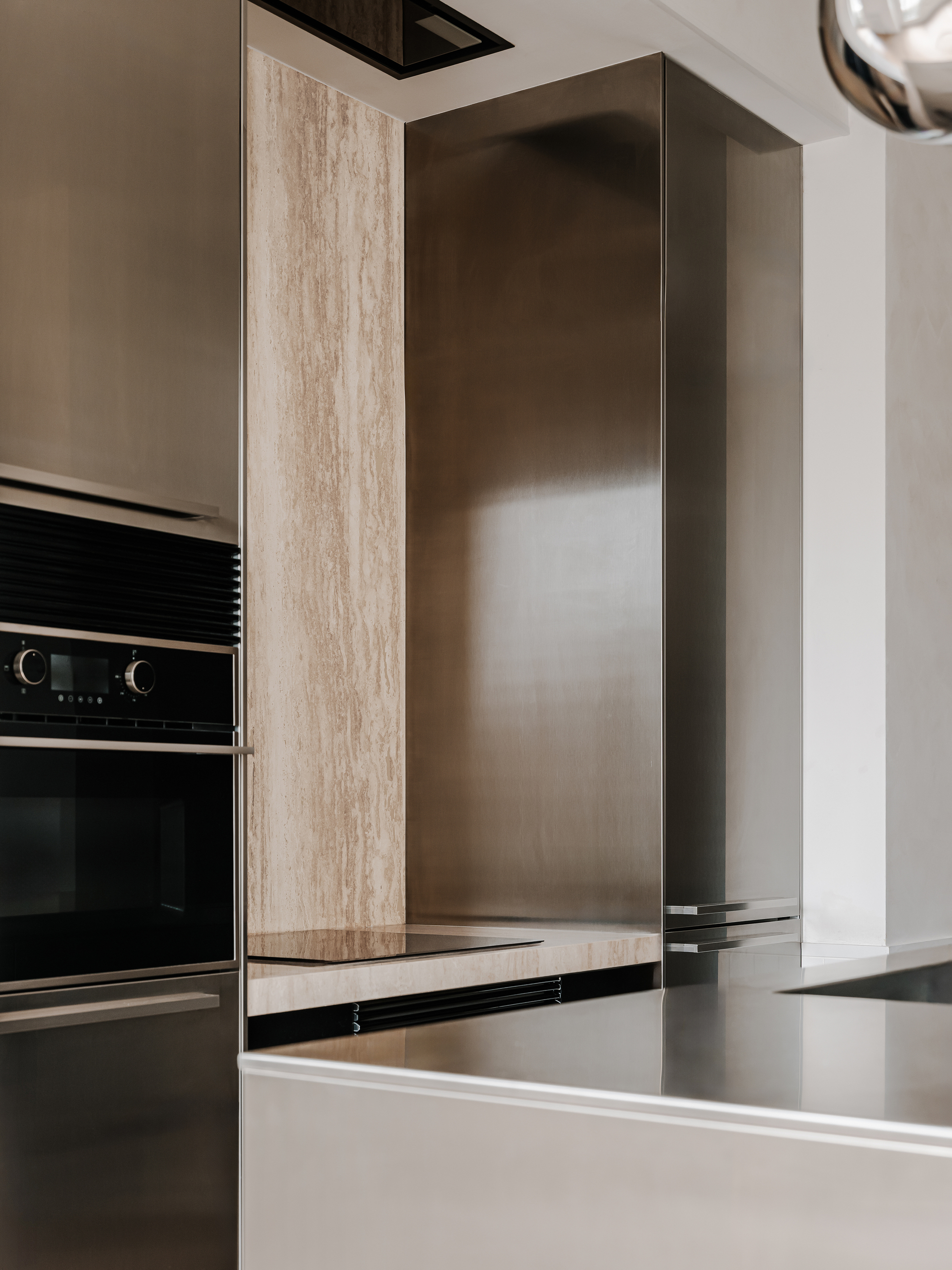 Close-up of the kitchen counter edge where polished stainless steel meets timber veneer column