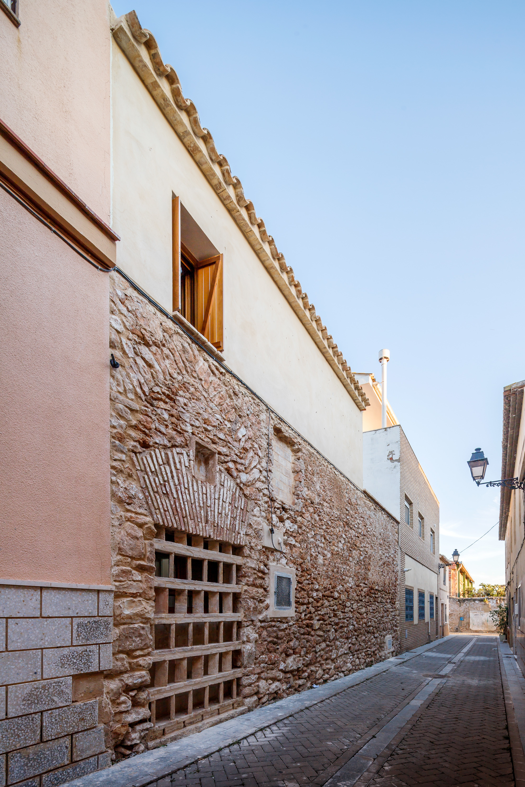 Street facade showing terracotta brick grate set into exposed stone wall beneath smooth white upper story