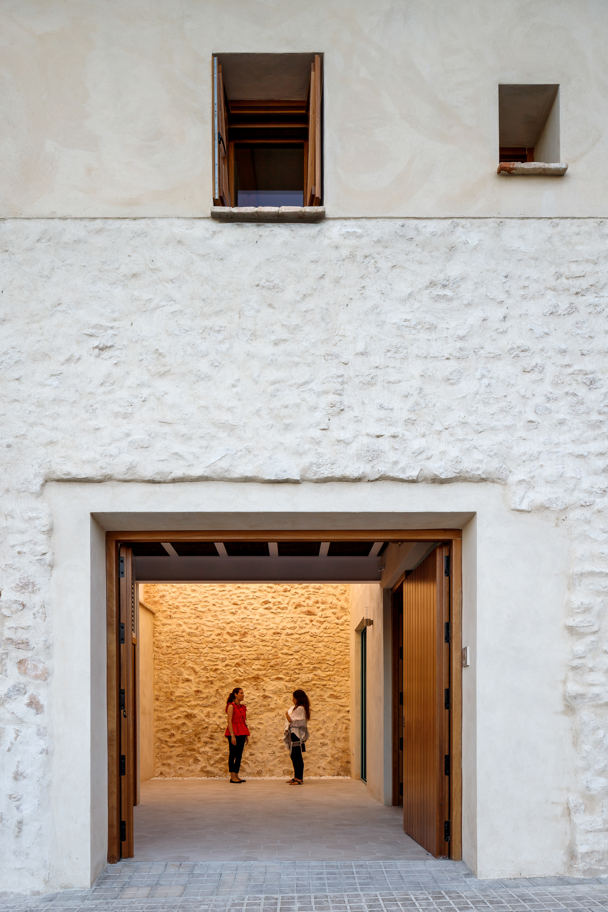 Large timber-framed entrance opening with exposed beam ceiling and two figures inside the stone-walled interior