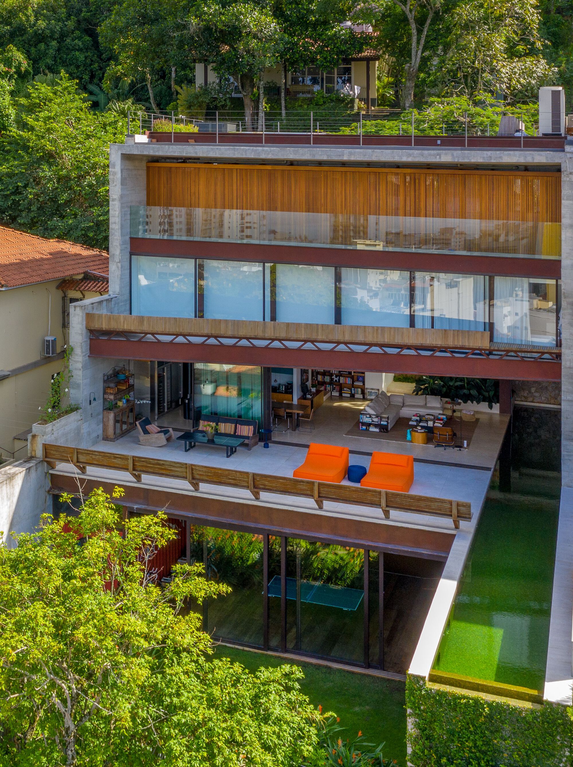 Facade showing staggered levels with timber louvers and rooftop garden beyond trees