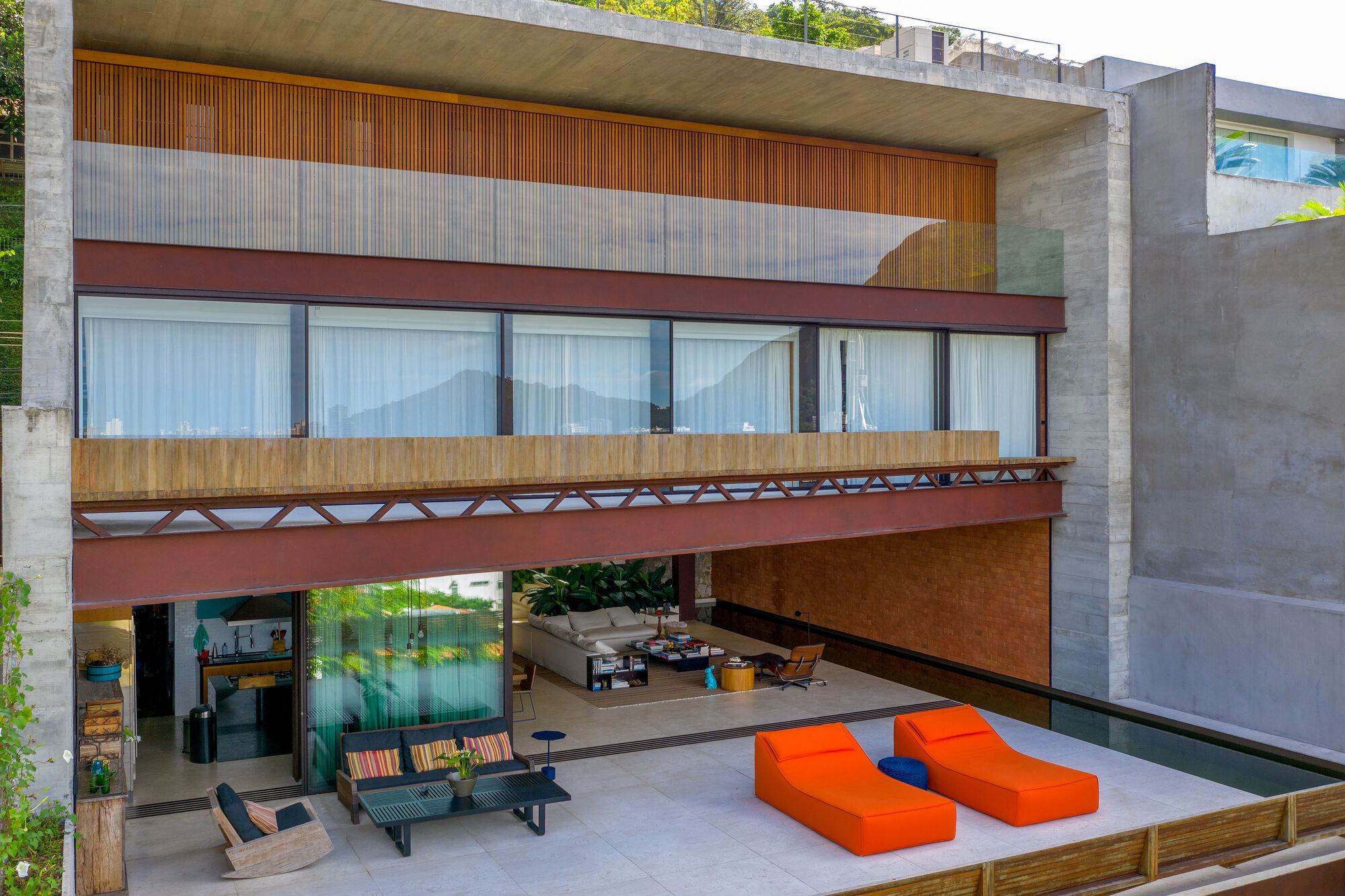 Open terrace with orange loungers beneath cantilevered floors and timber lattice railings