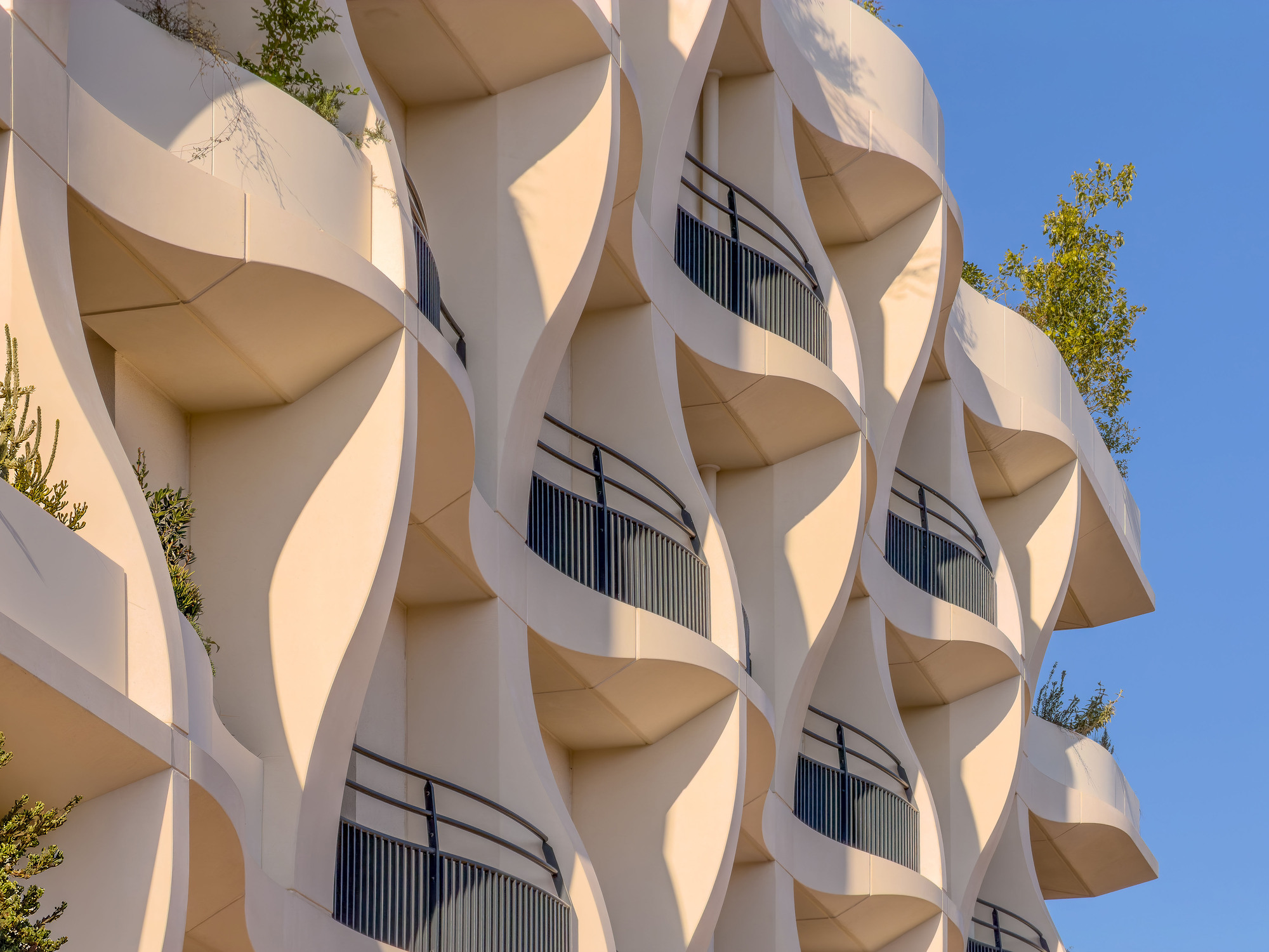 Close-up of the sinuous balcony edges and metal railings with scattered greenery between floors