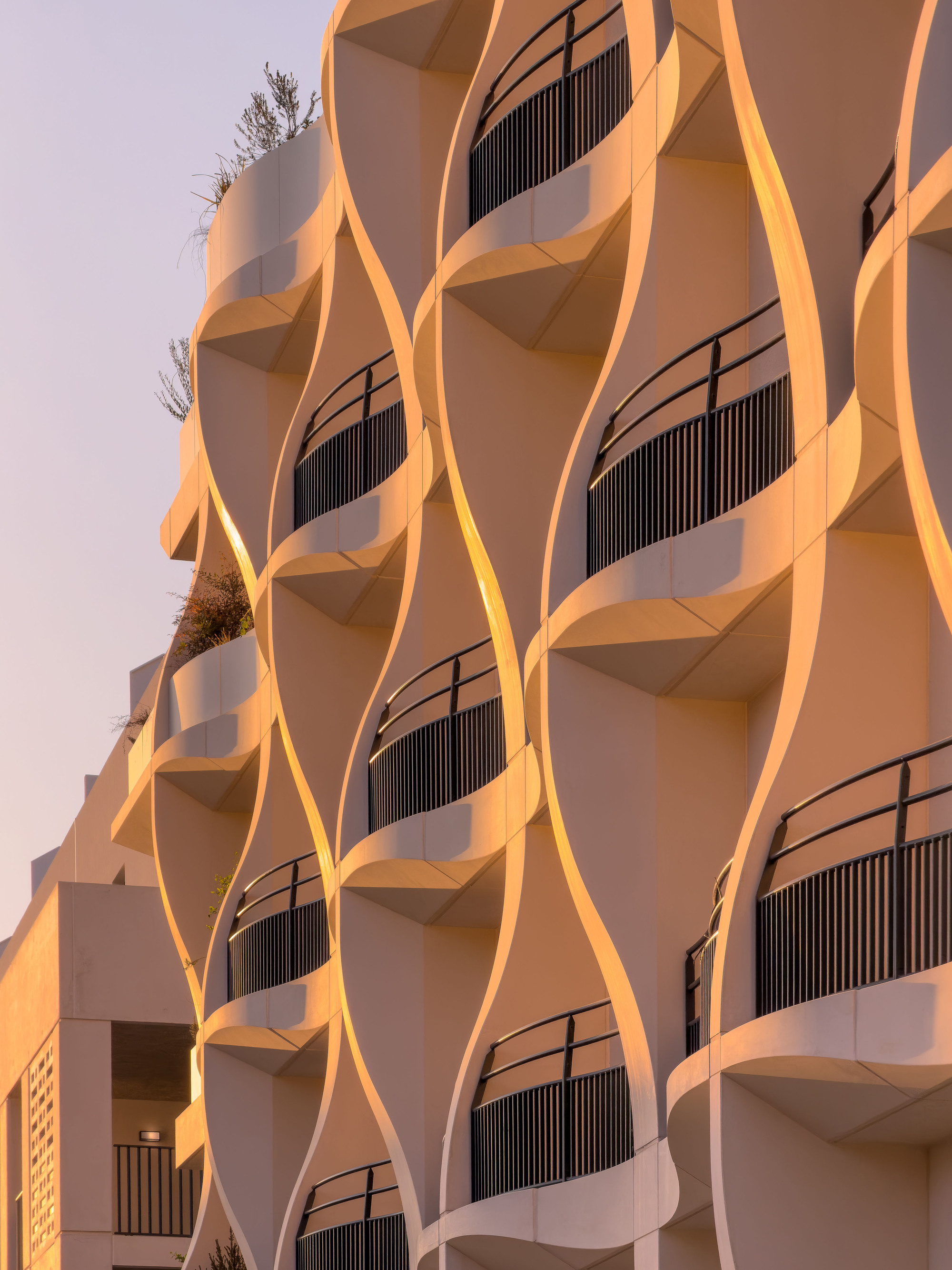 Close-up of the rippling facade with vertical slat screens at dusk