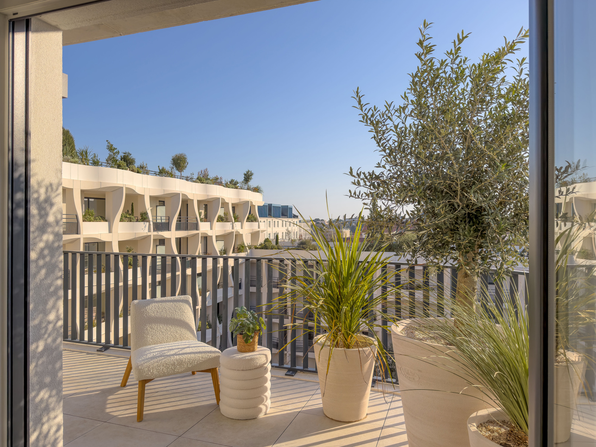 Private terrace with timber decking and slatted screen overlooking adjacent building volumes