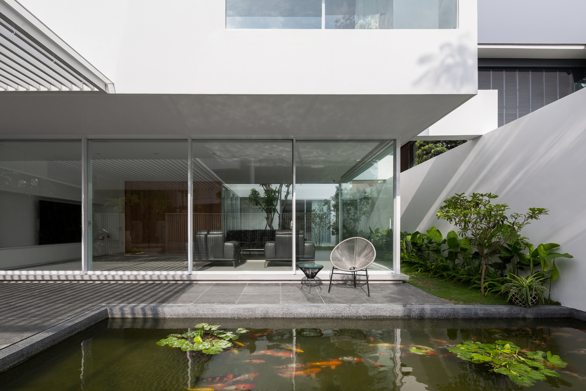 Internal courtyard with koi pond and concrete terrace beneath a cantilevered slab and glass walls