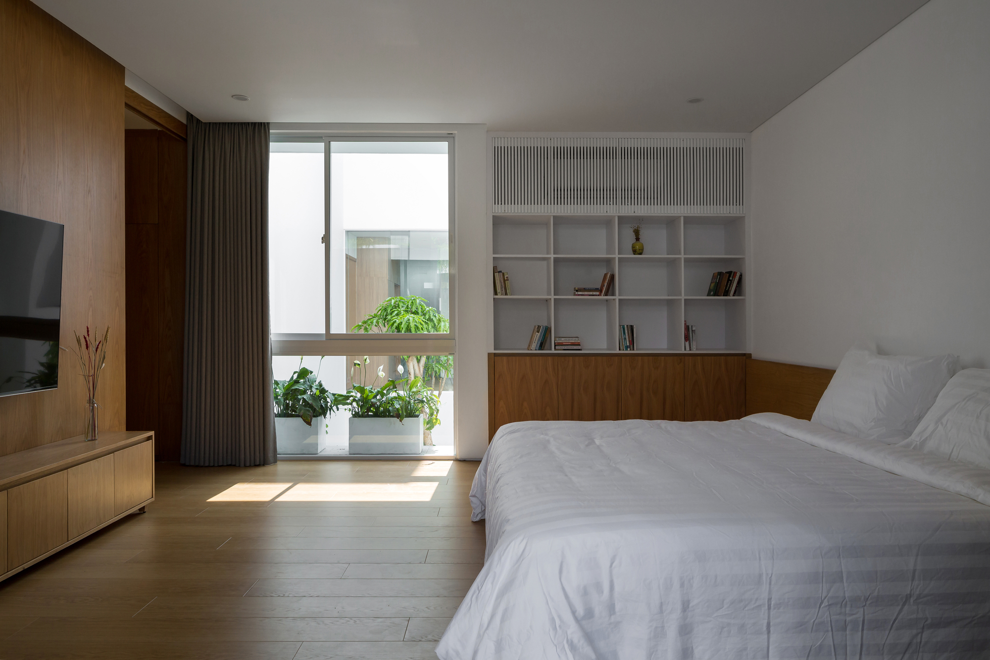 Bedroom with built-in wood and white shelving unit and balcony view of potted plants