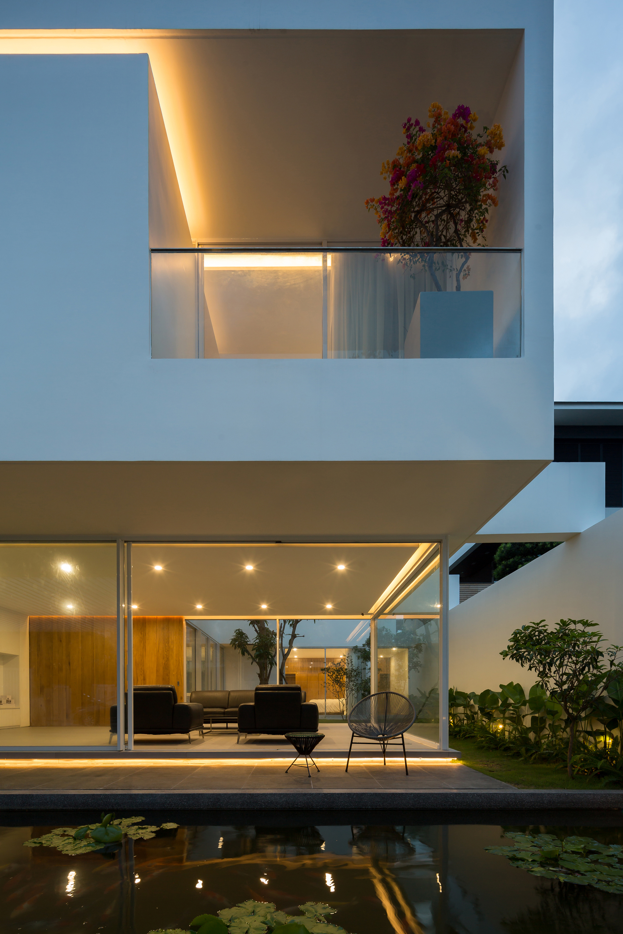 Night view of the illuminated courtyard terrace and reflecting pool at dusk with stacked volumes