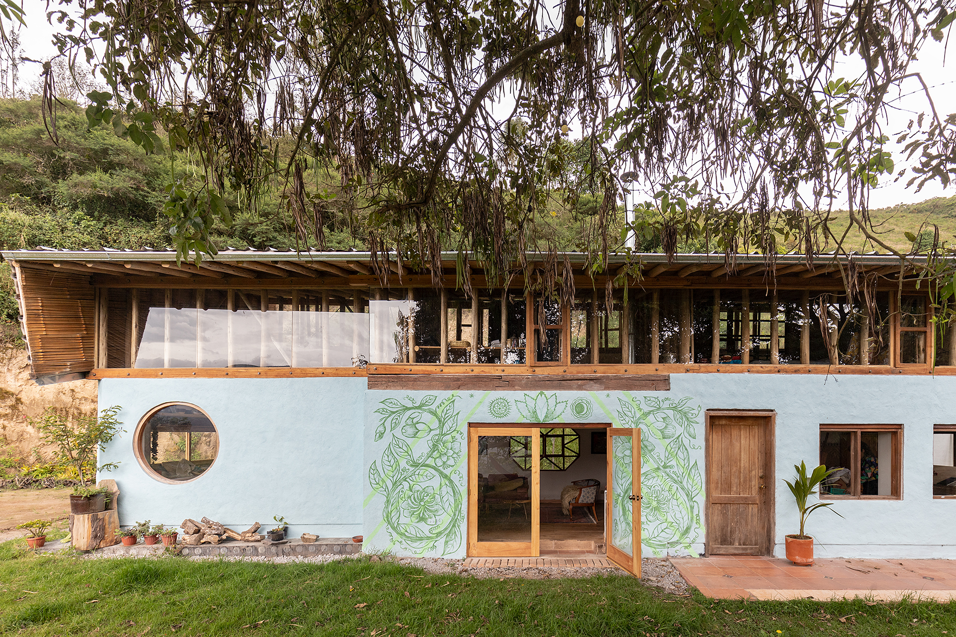 Two-storey facade with painted murals, a circular window, timber-framed upper level, and eucalyptus trees overhead