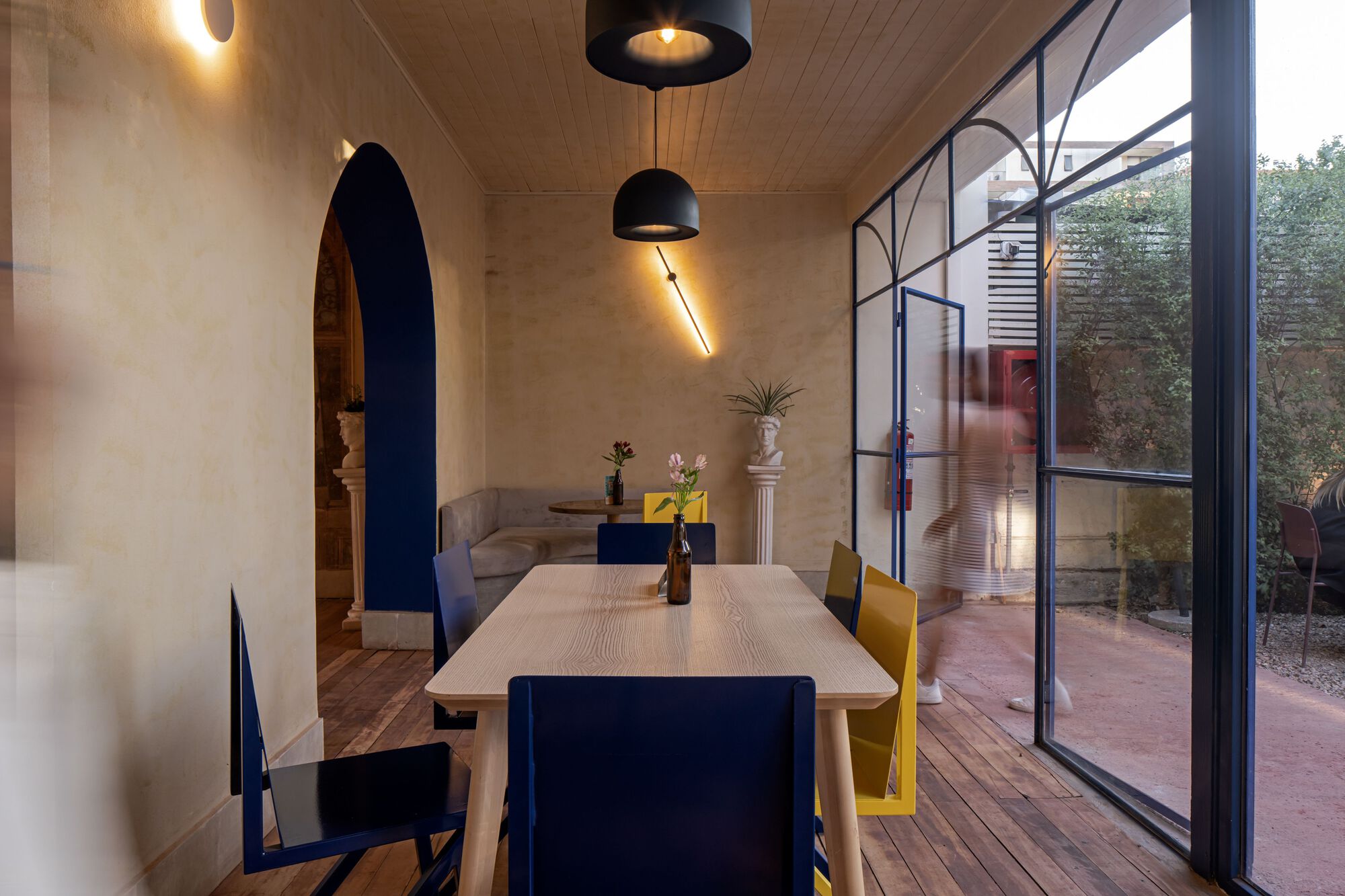 Dining room with timber plank ceiling and blue steel glazed wall overlooking a courtyard