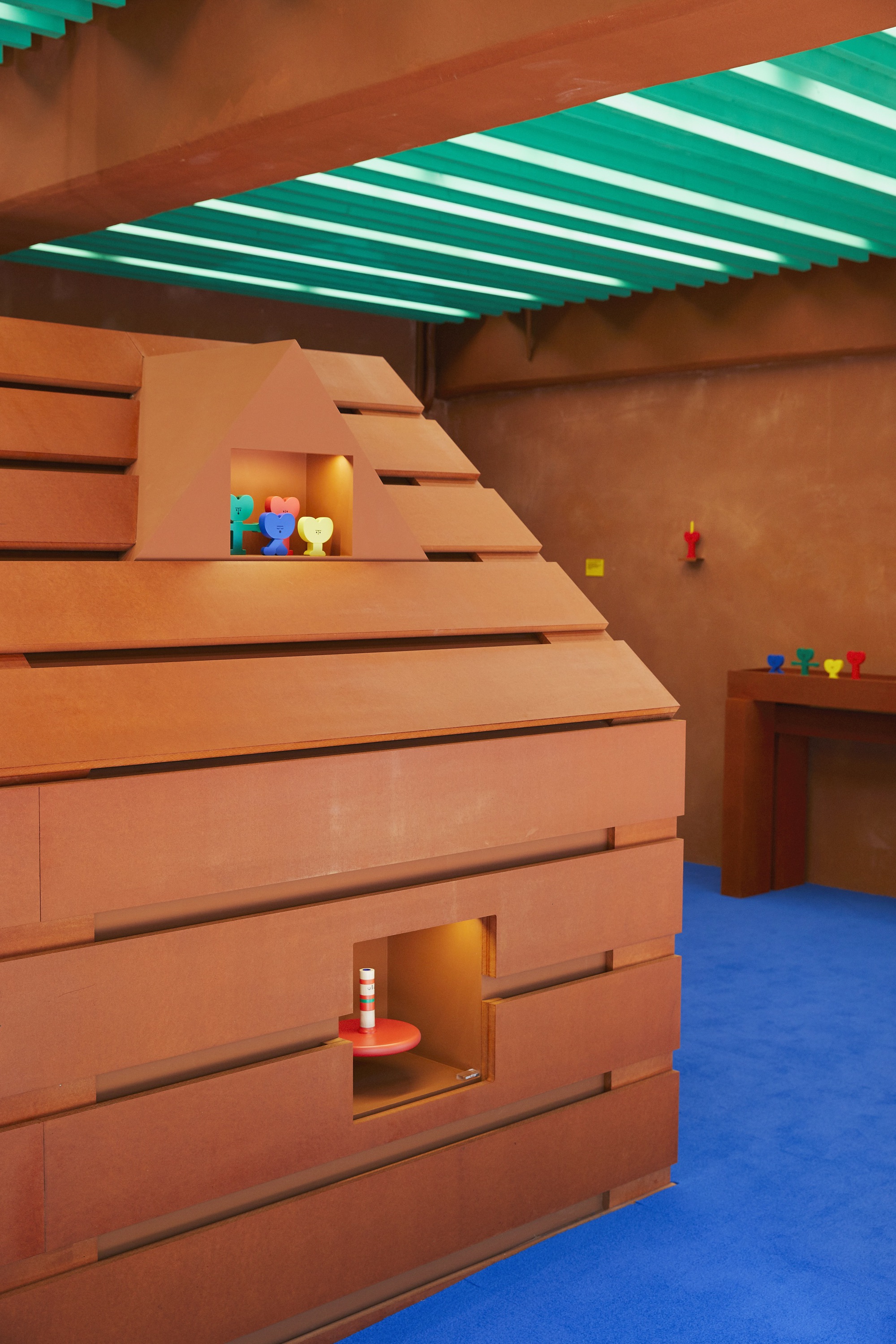 Corner view of stepped timber structure with square openings and colorful toys on shelves