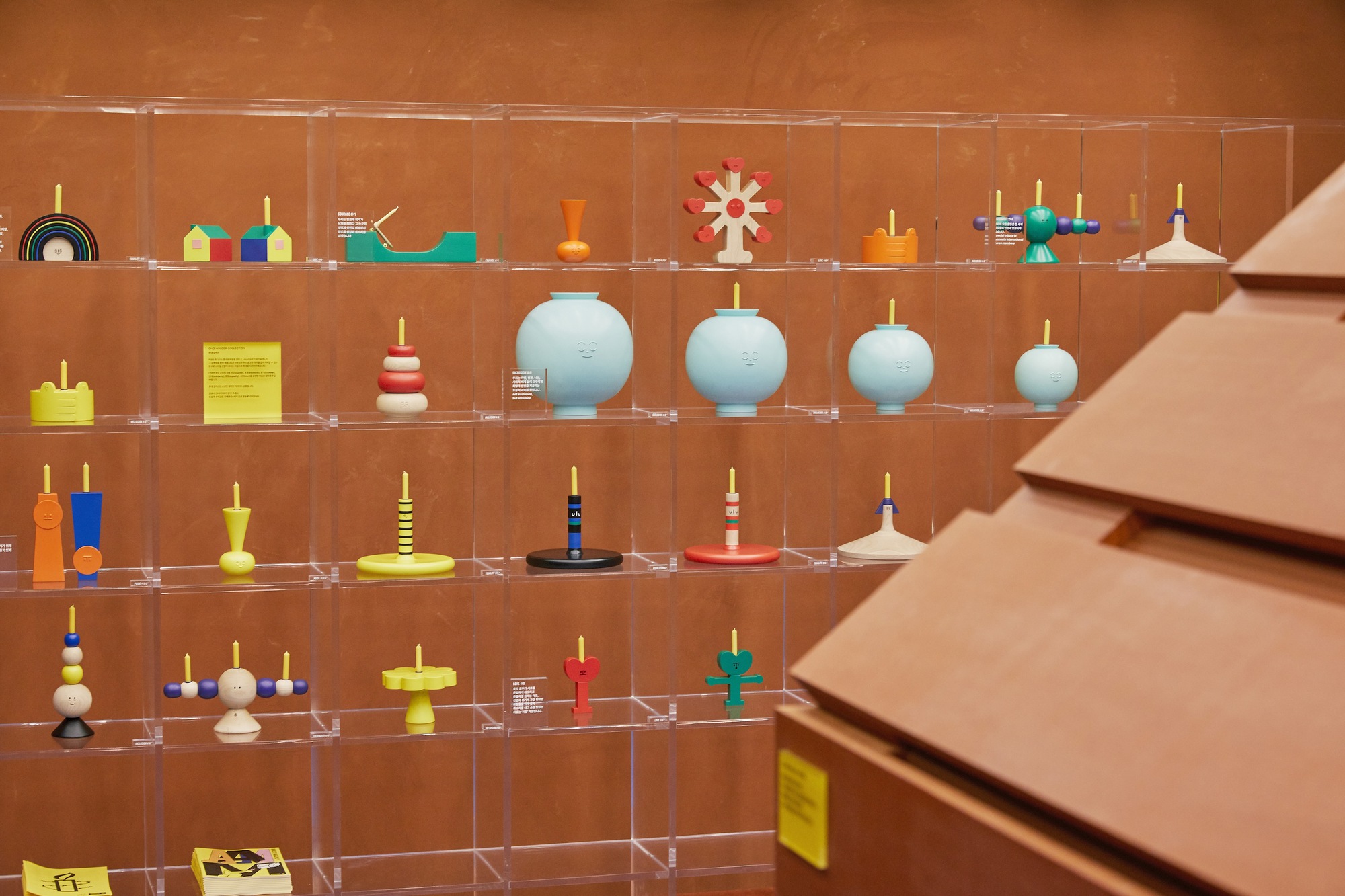 Clear acrylic display shelves holding colorful spinning tops against warm terracotta walls