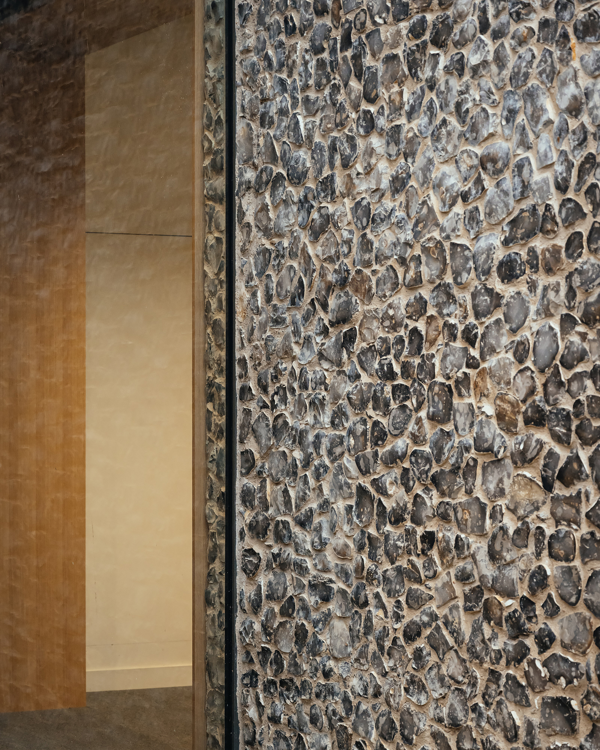 Detail of cobblestone wall meeting smooth limestone panels with a metal trim separating the two textures