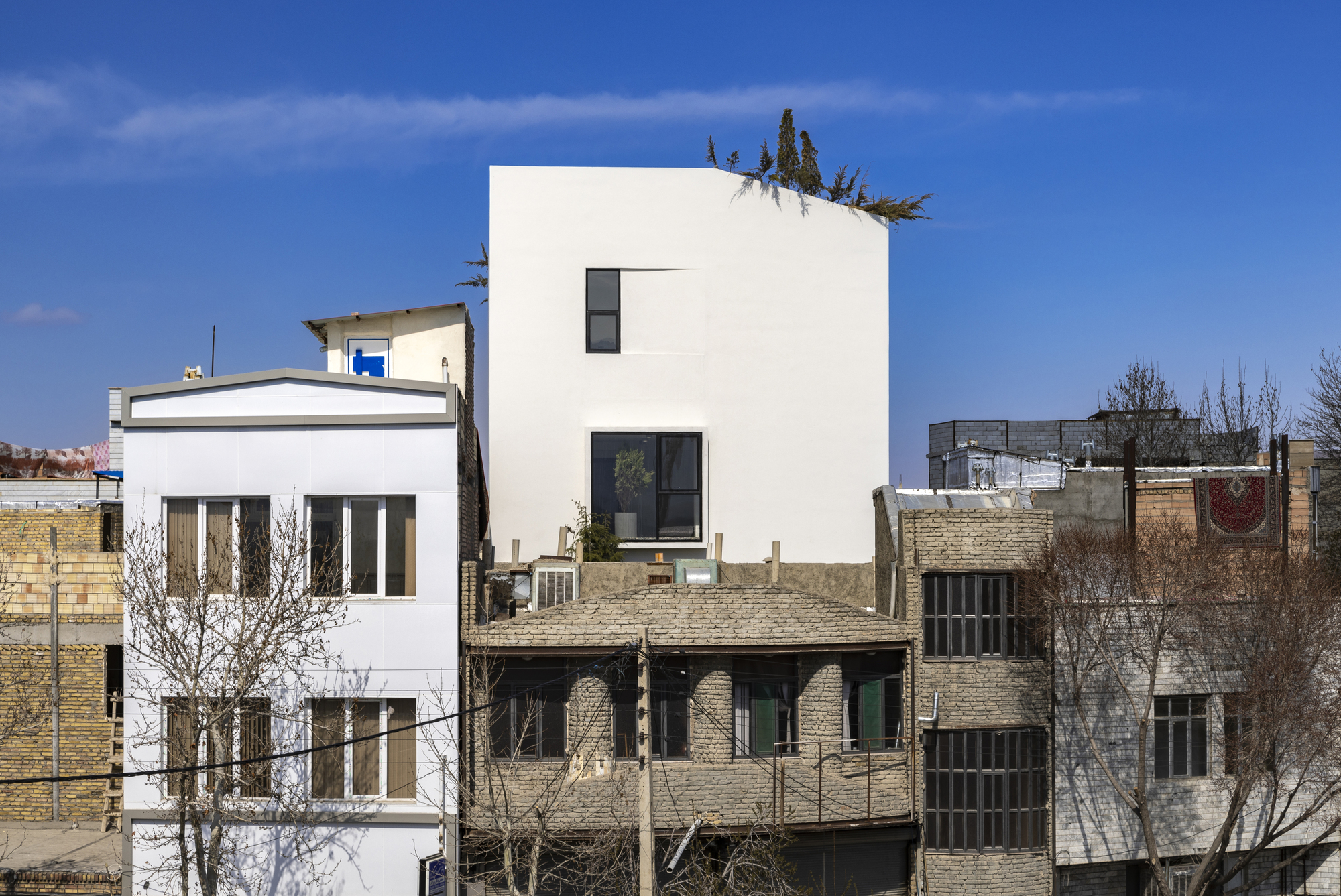 White tower rising above adjacent low brick buildings in a dense neighborhood under clear sky