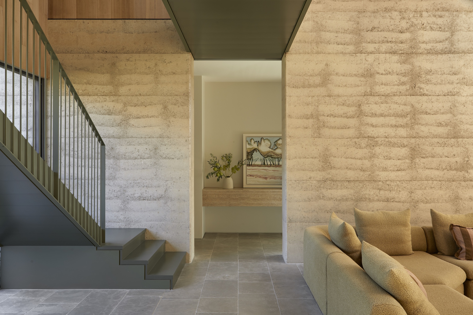 Interior view of folded steel staircase rising between board-marked concrete walls