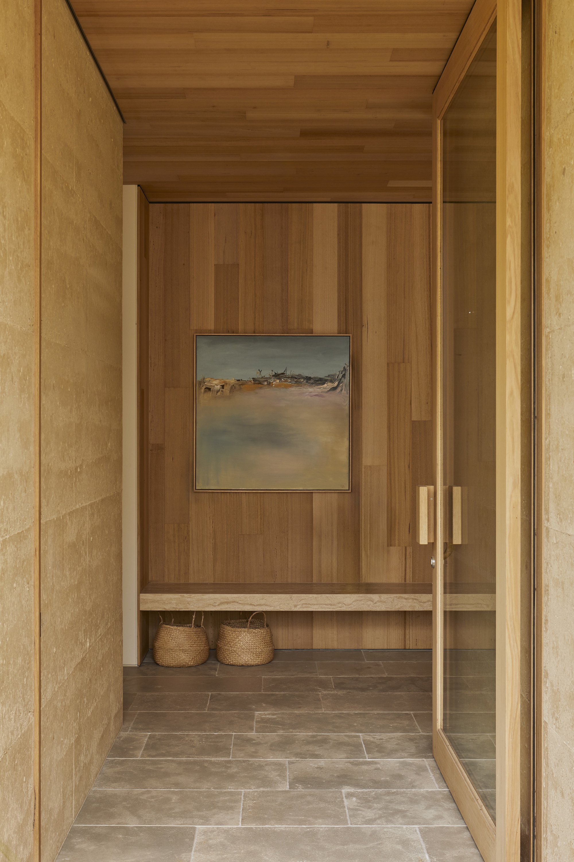 Entry vestibule with timber-lined walls and ceiling leading to a bench with woven baskets below