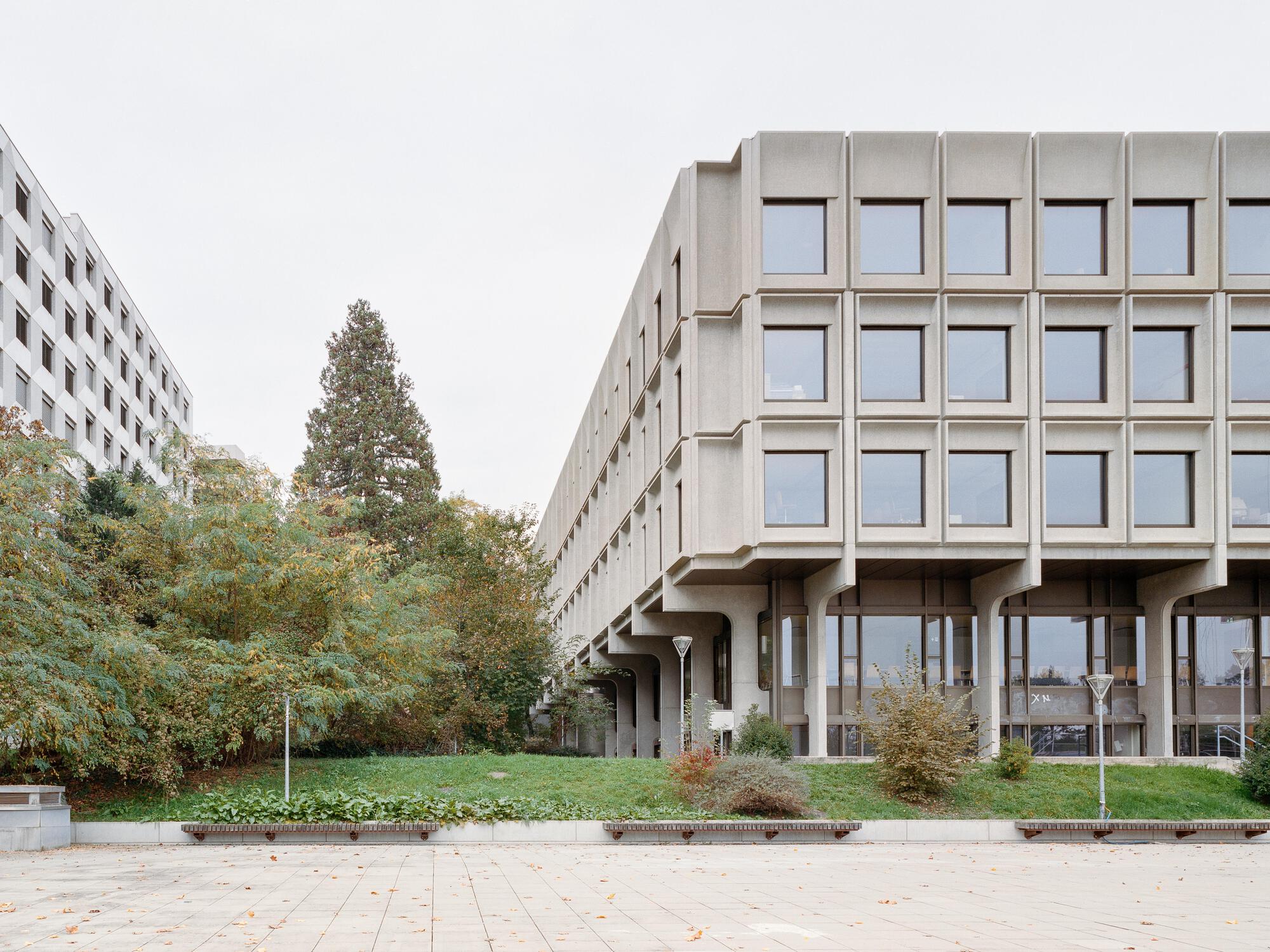 Corner view of the precast concrete facade on pilotis with paved plaza in foreground