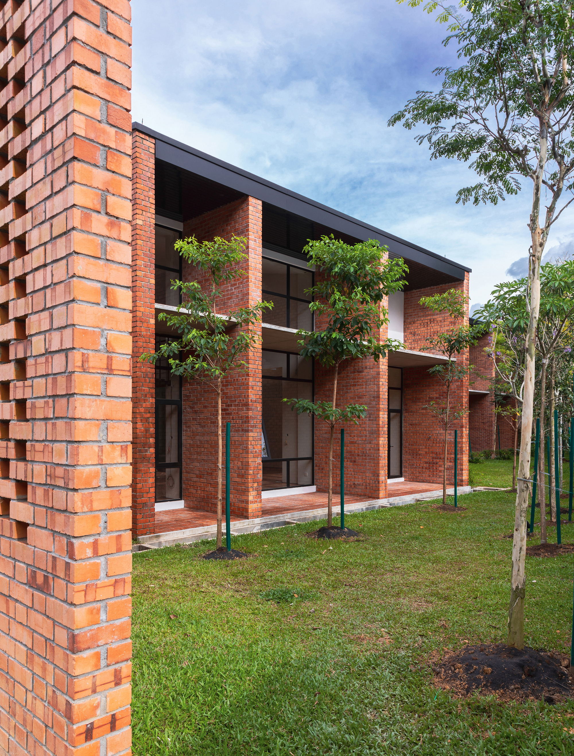 Side view of brick facade with deep overhangs and glazed openings facing a grassed lawn