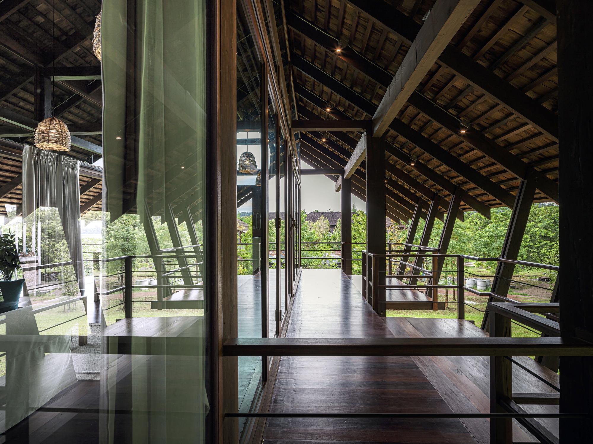 Corridor with dark timber floors and green glass partitions under a pitched roof with exposed timber trusses