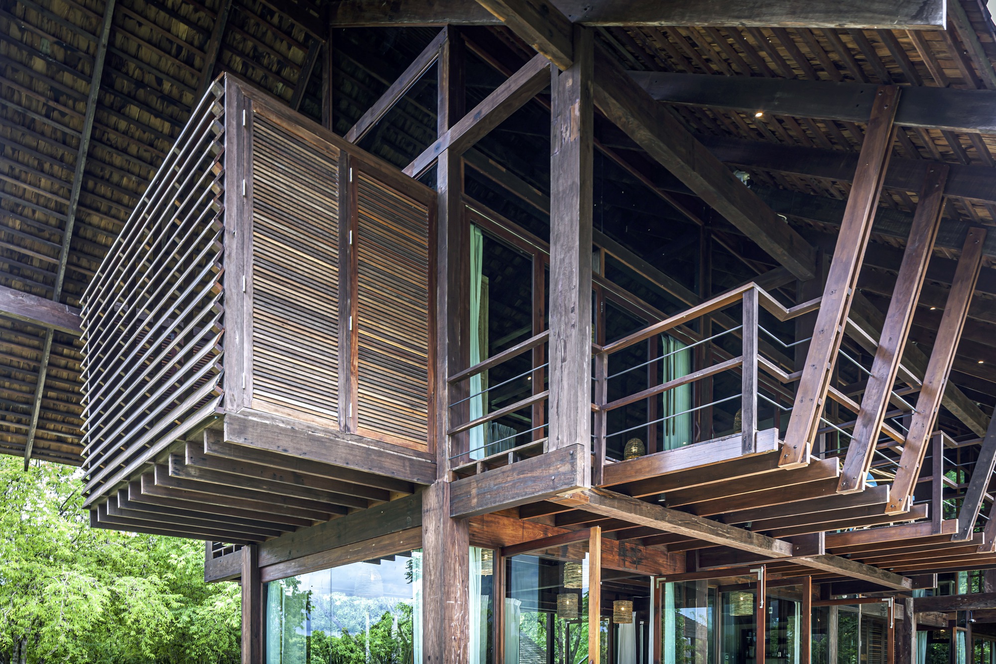 Underside view of cantilevered timber balcony with horizontal slat screens and exposed structural beams