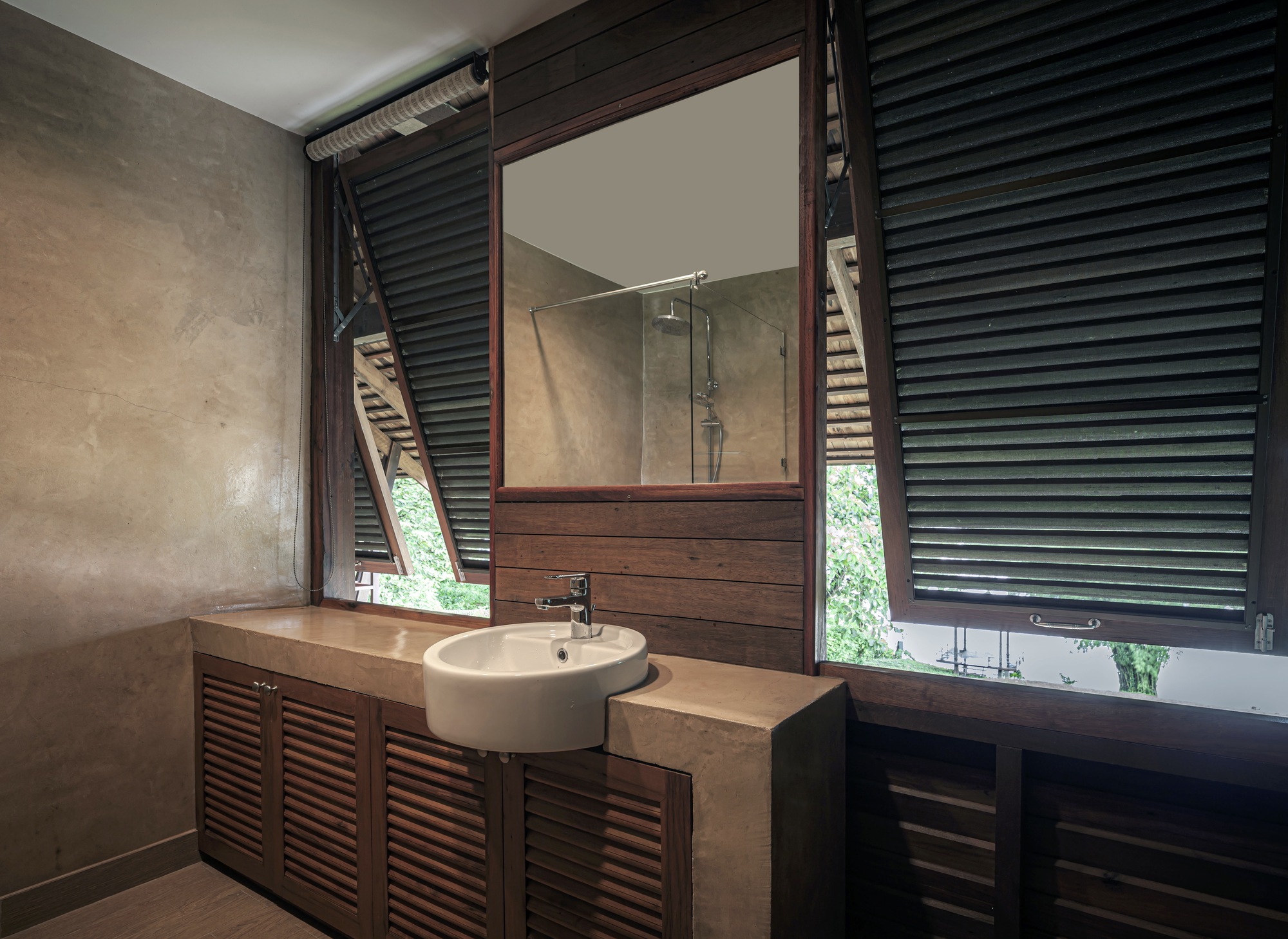Bathroom vanity with white basin on louvered timber cabinetry below horizontal slatted shutters and mirror