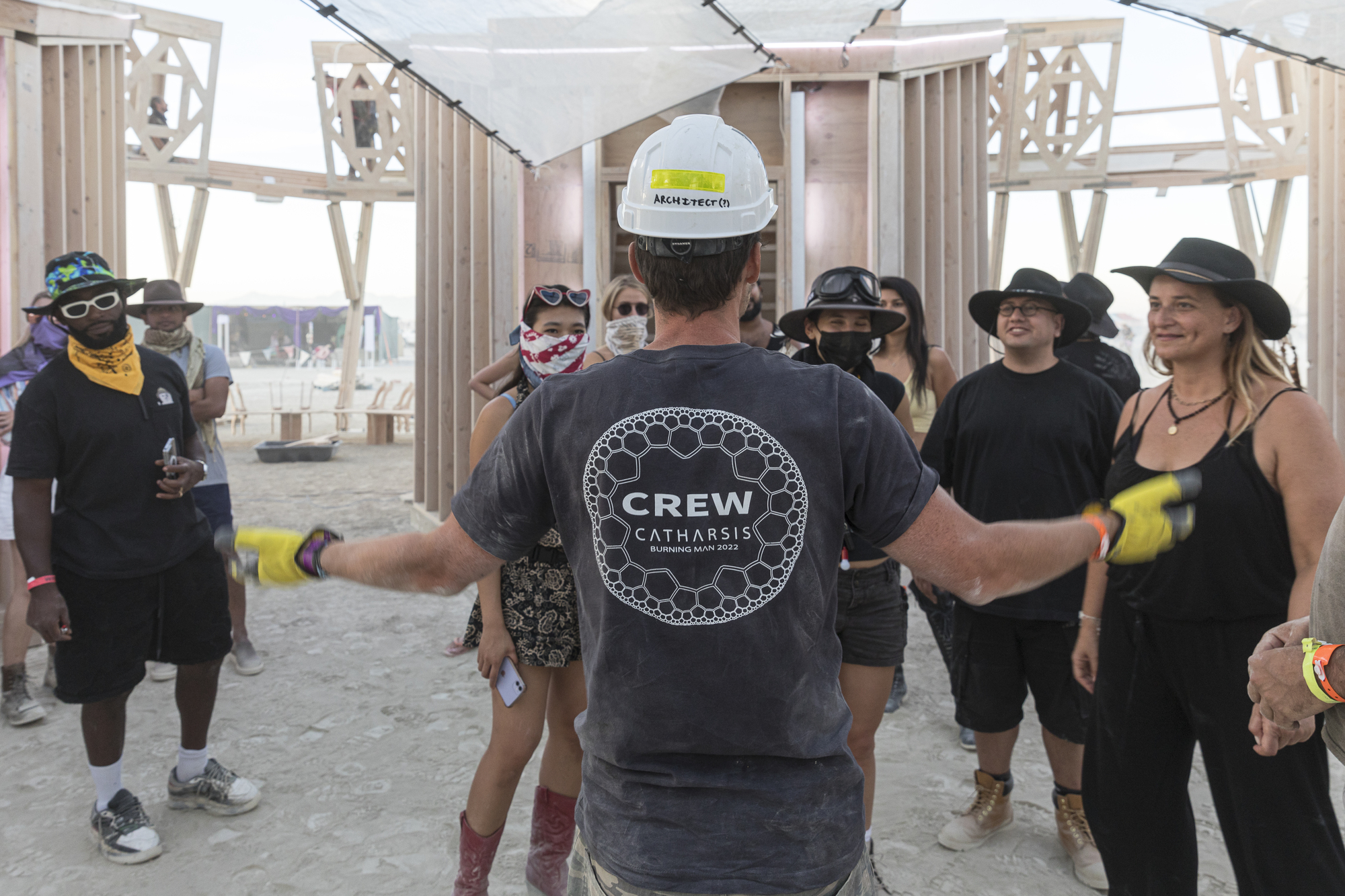 Interior gathering space with timber frame structure and fabric ceiling during a guided tour