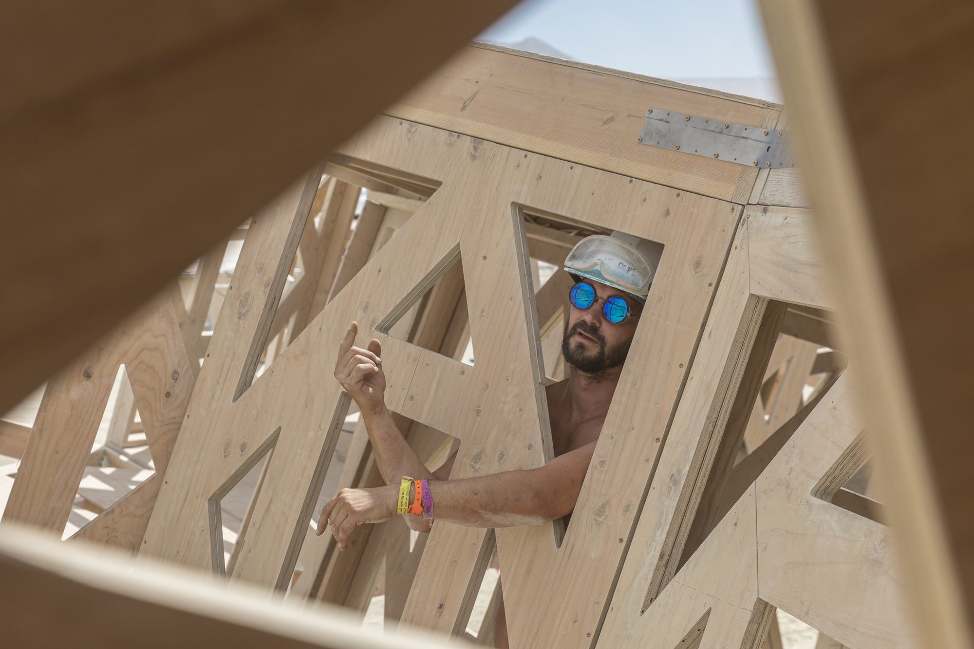 View through triangular plywood openings showing a builder working on the structural framework