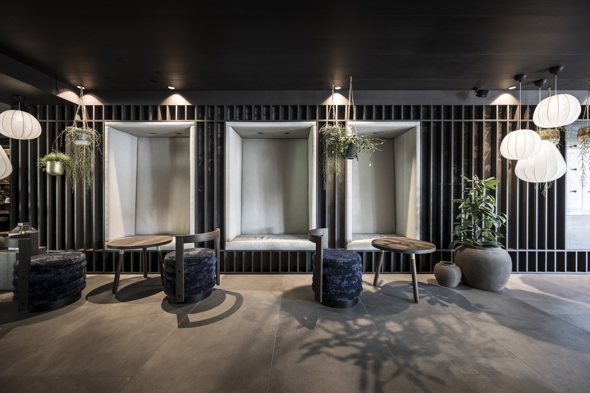 Interior seating area with three illuminated niches, vertical slat dividers, and hanging spherical pendant lights