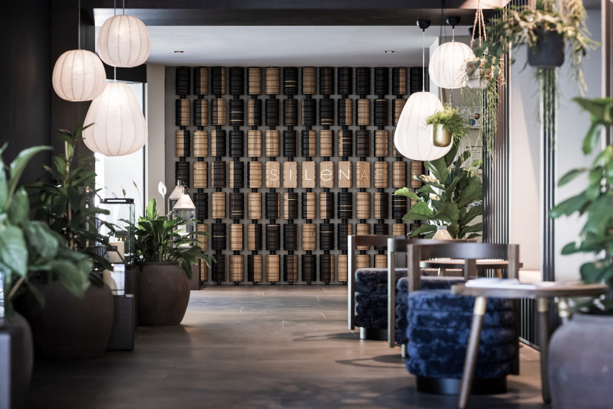 Lobby space with checkered acoustic panel wall, spherical paper lanterns and potted tropical plants