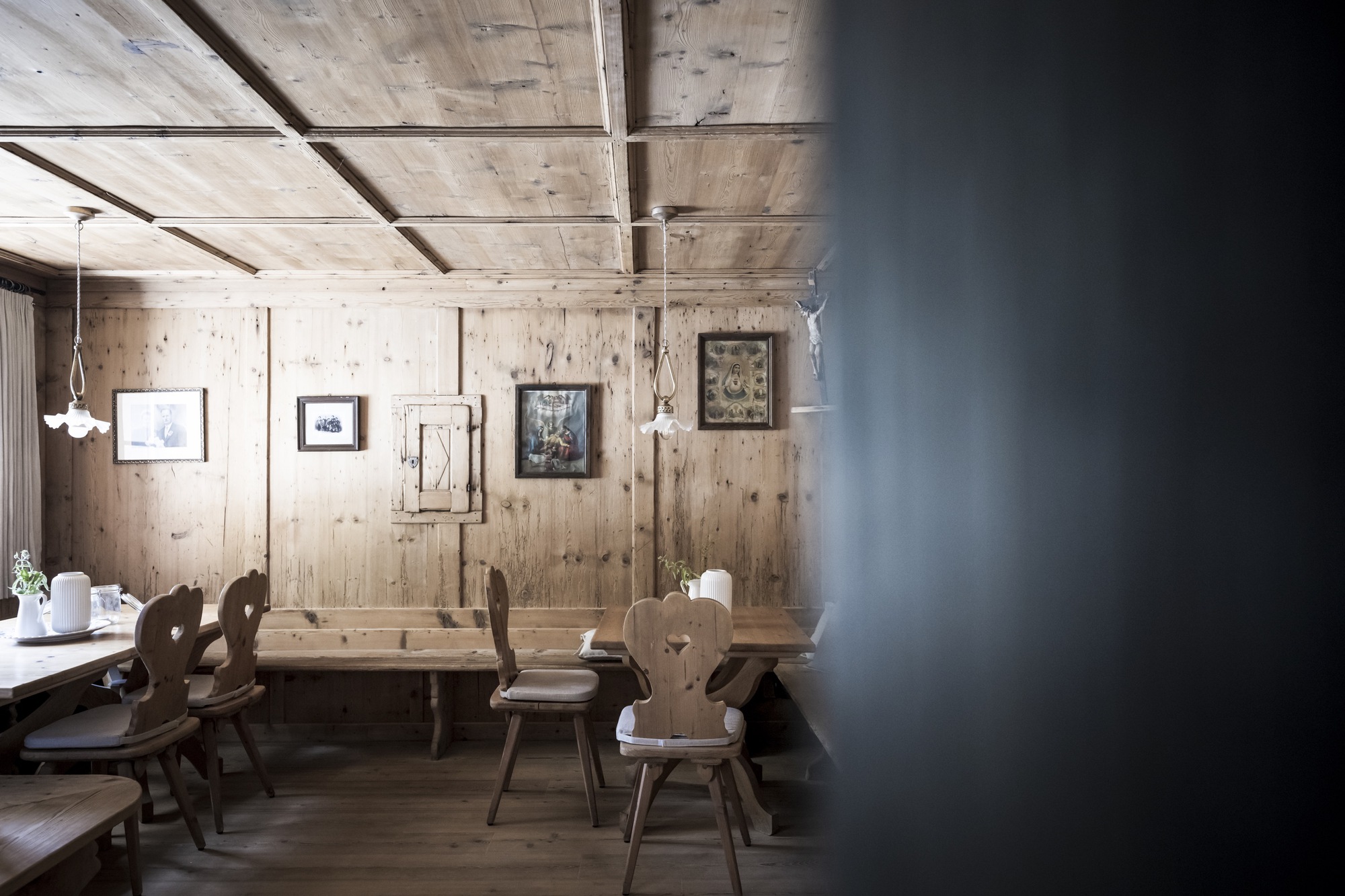Dining alcove with weathered timber plank walls, exposed ceiling beams and traditional carved wooden chairs