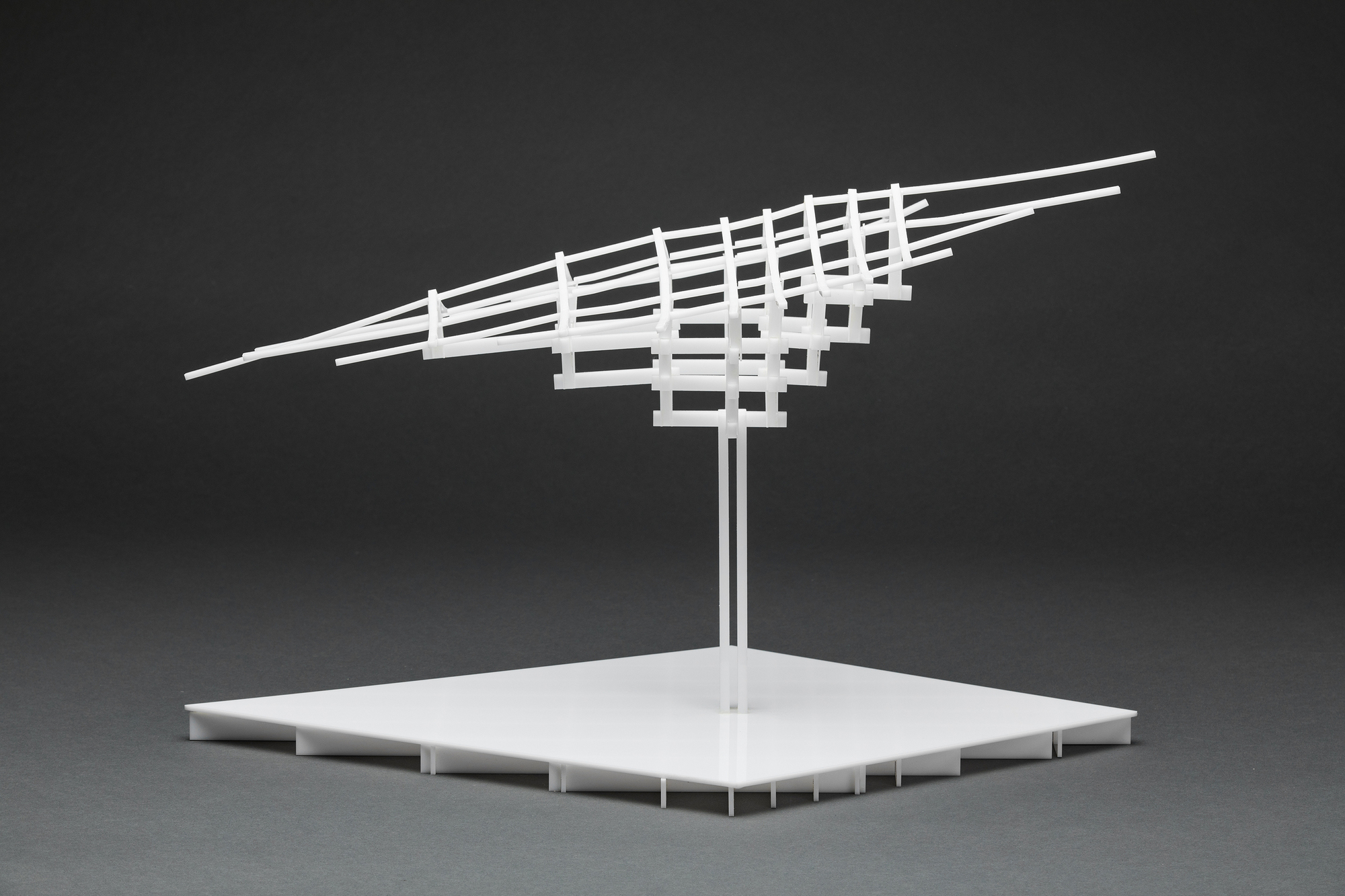 Physical model of a tilted gridded roof canopy supported by twin columns on a flat platform base