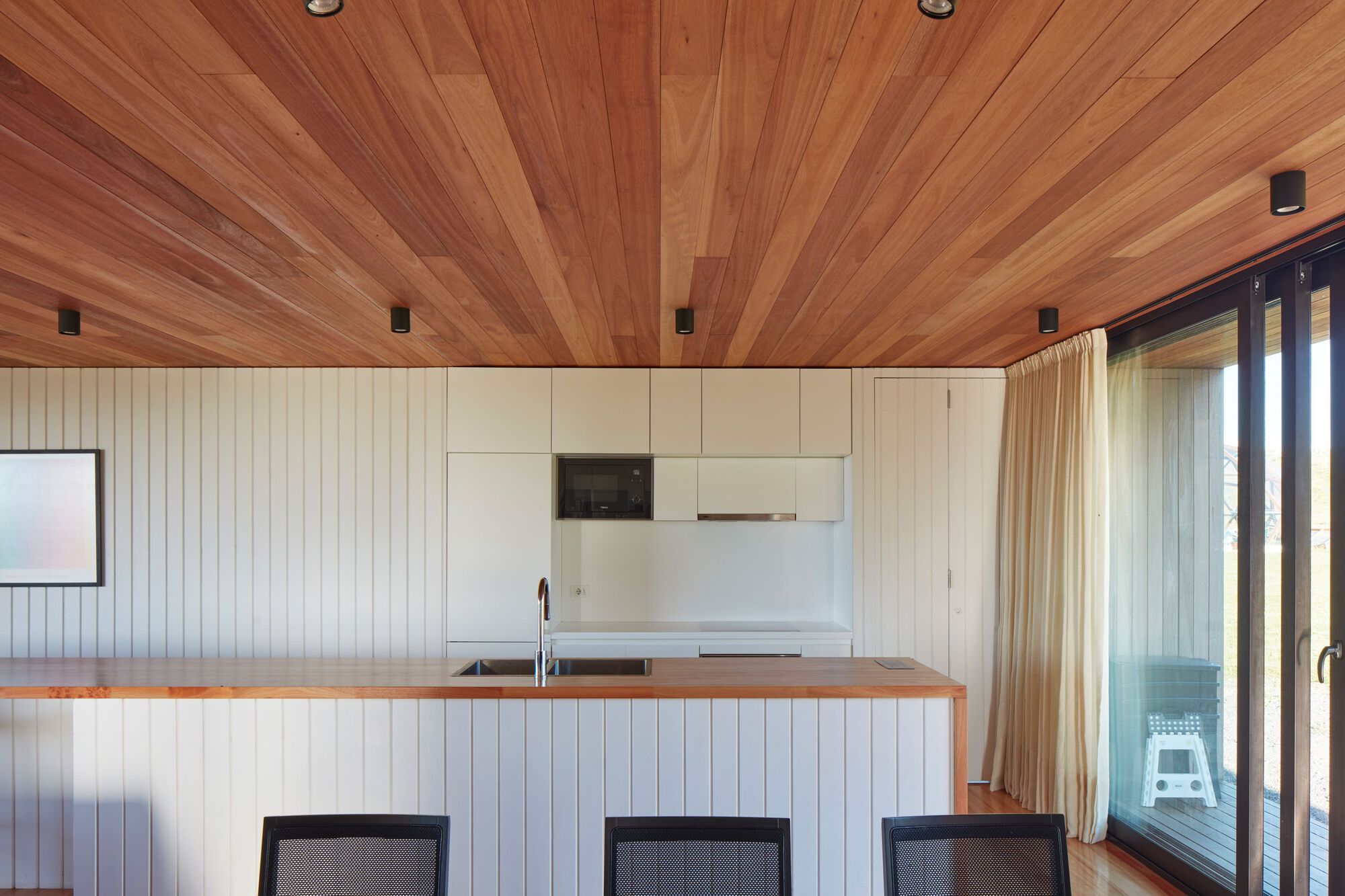 Kitchen counter with timber-lined ceiling radiating from a central spine beam