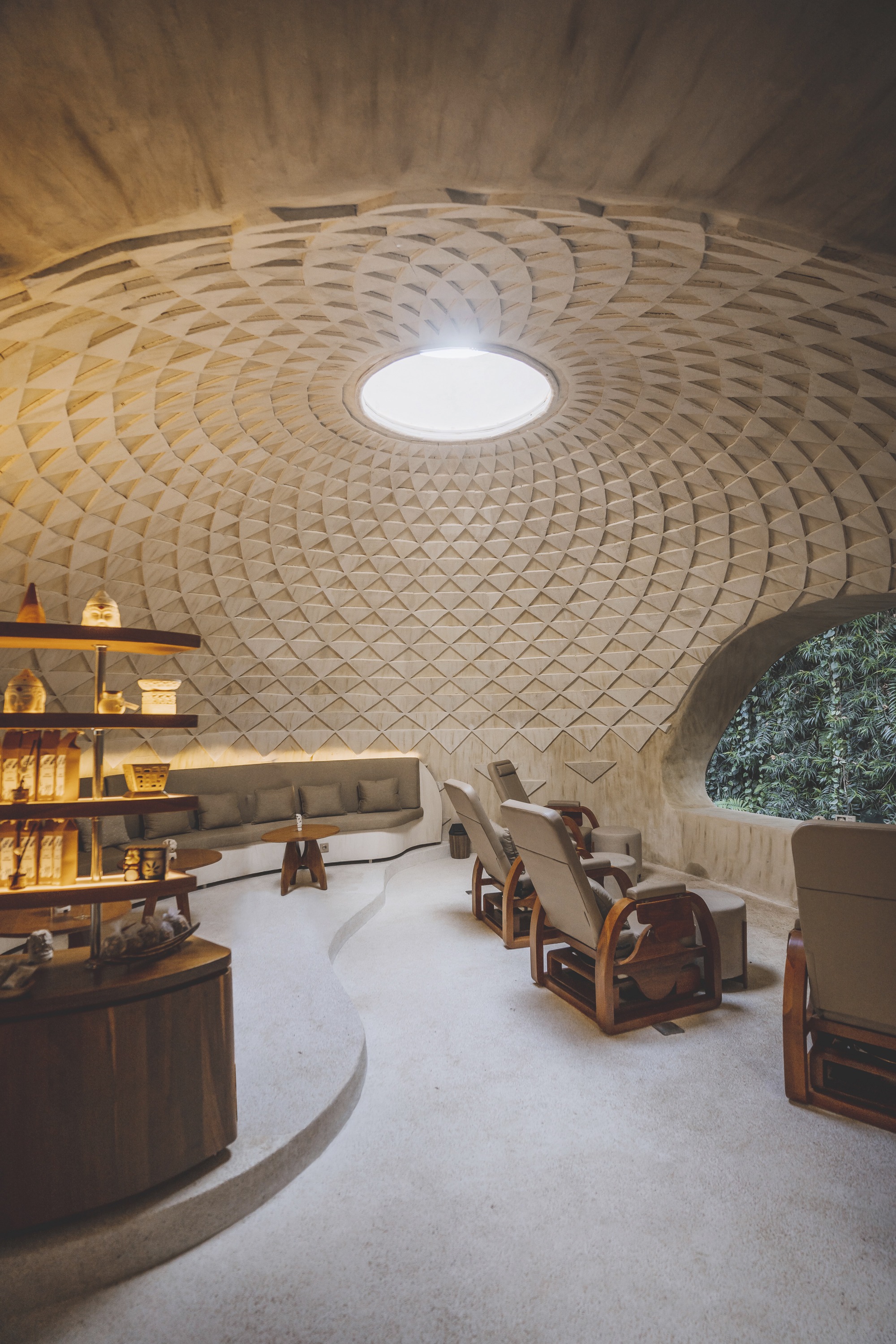 Circular interior space with a patterned timber dome ceiling and central oculus above a curved seating area