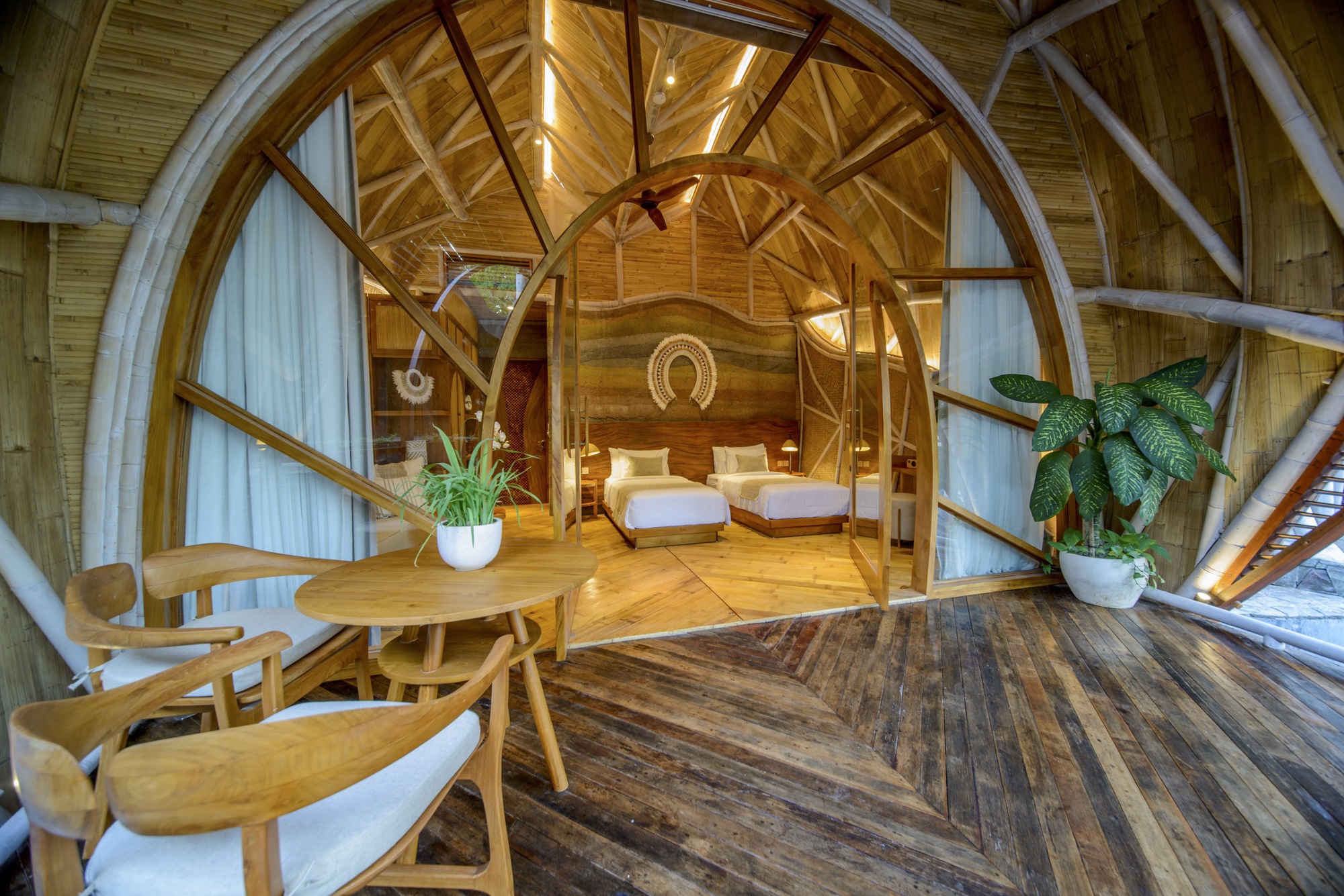 Interior view through arched timber portal into sleeping quarters with exposed wood beams and vaulted ceiling