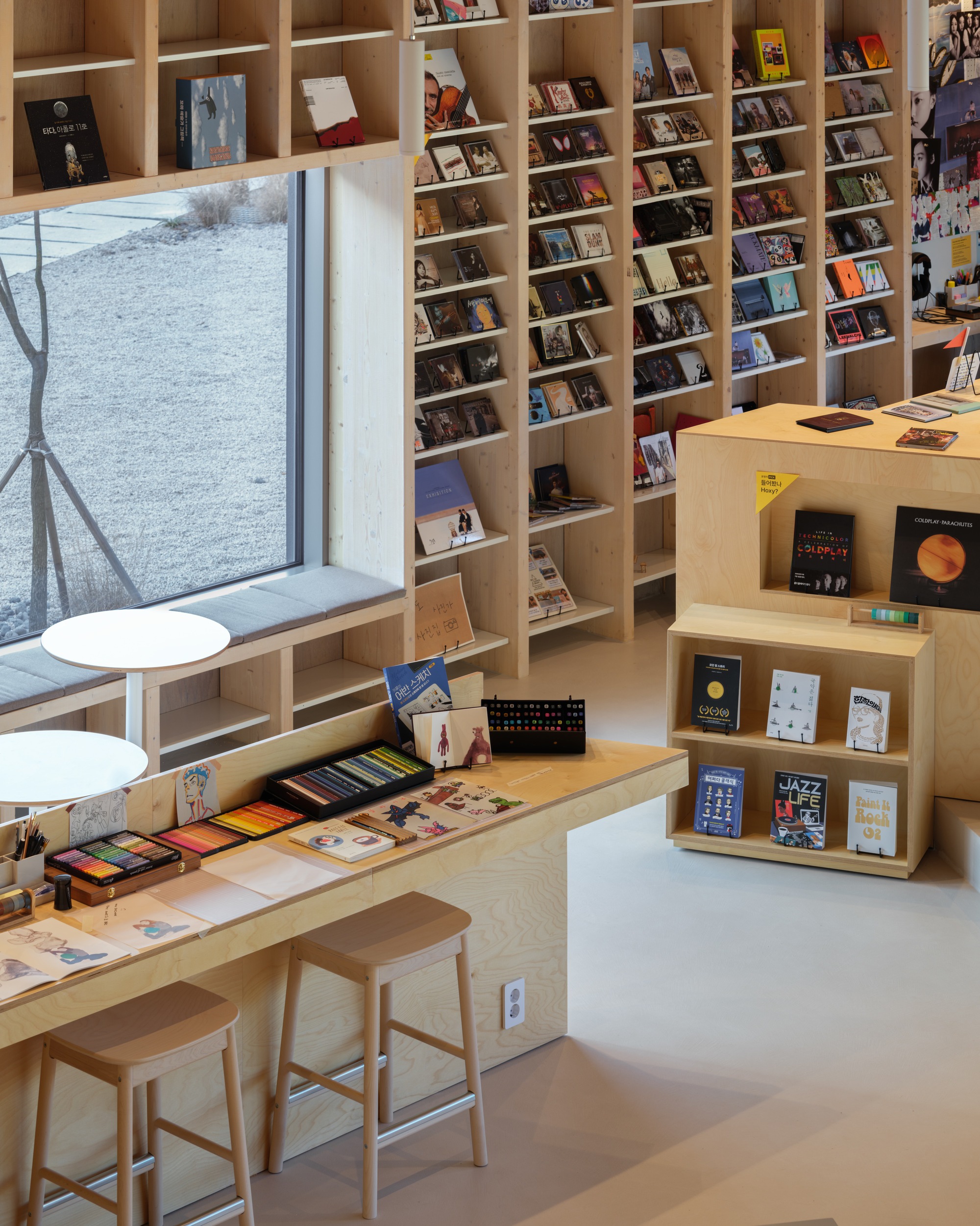 Plywood bookshelf wall with window seat overlooking a winter landscape outside