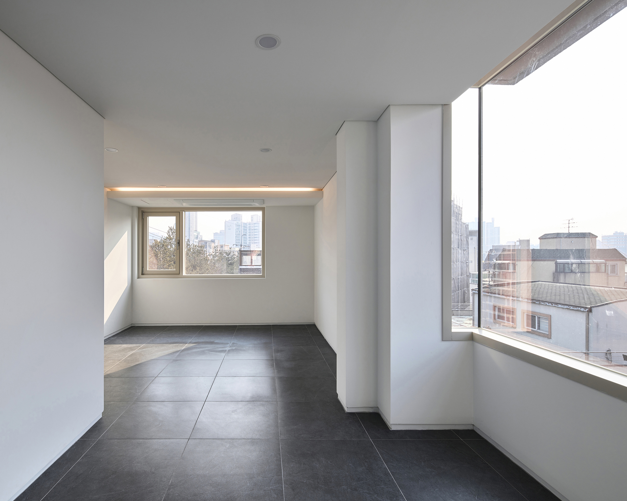 Interior corner with angled window walls and integrated linear lighting above the smaller opening