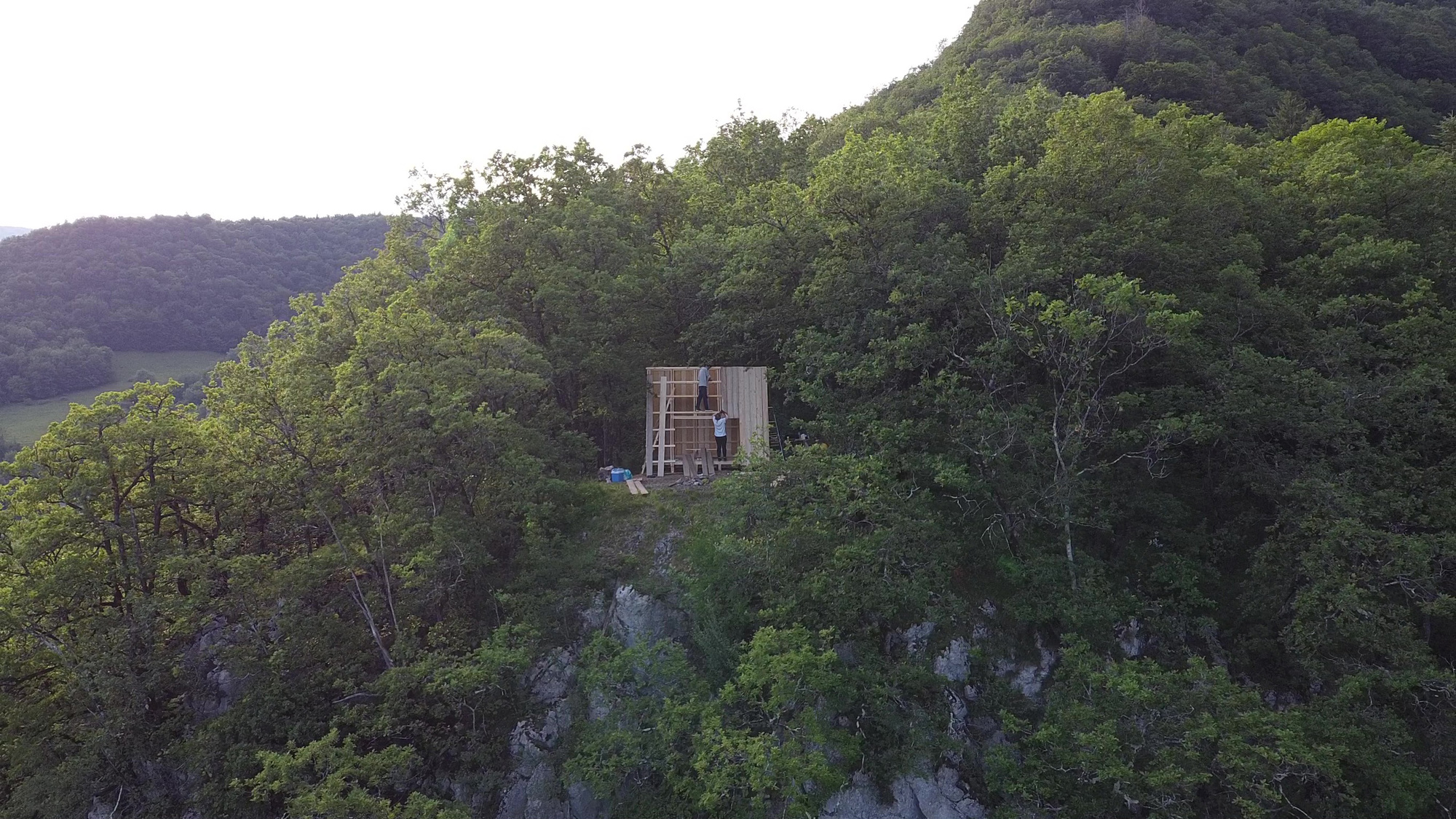 Distant view of the timber structure perched on a forested hillside at twilight