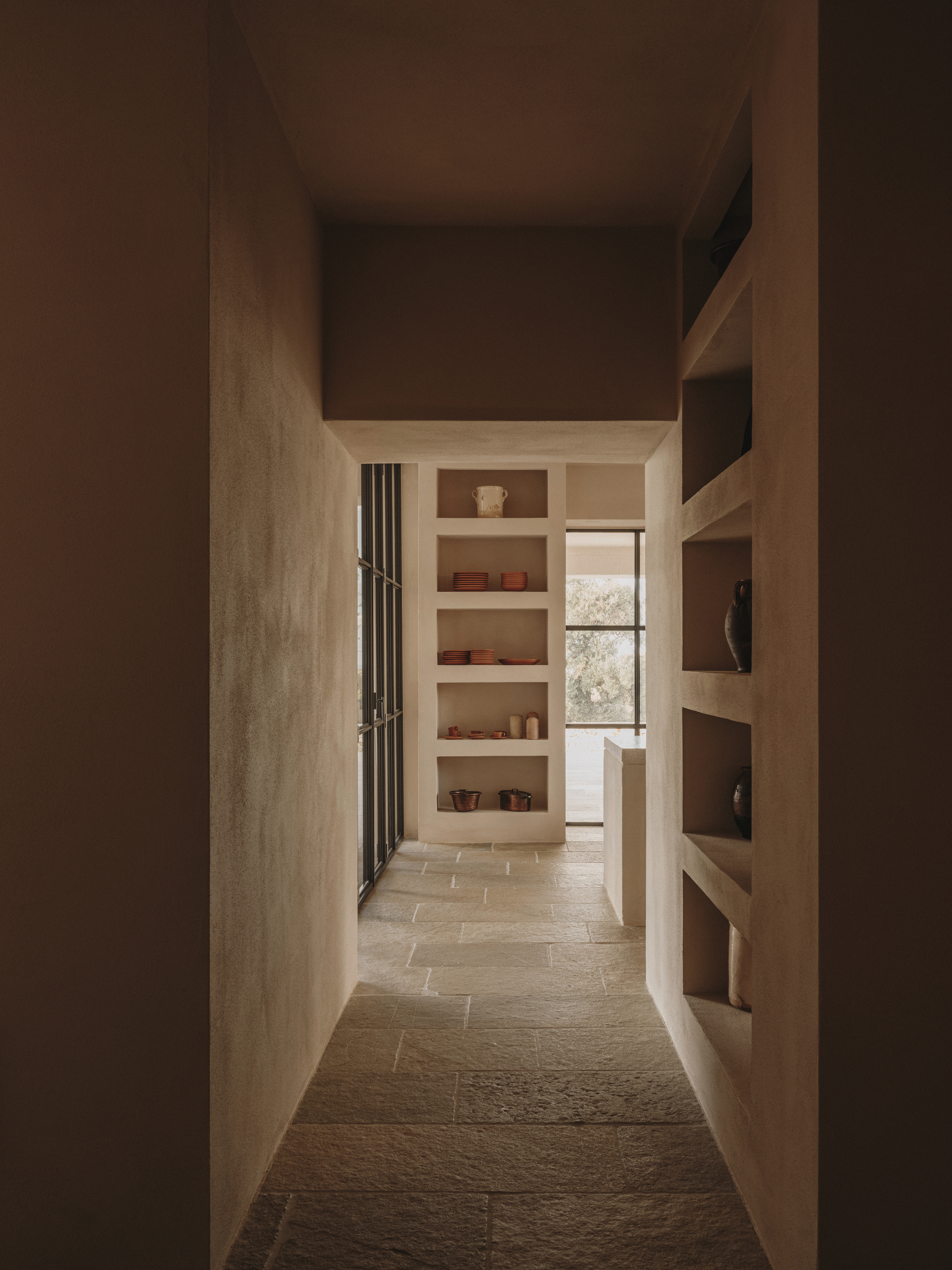 Narrow corridor framed by built-in timber shelving with soft afternoon light filtering through