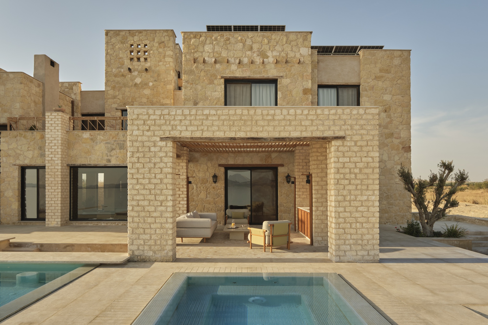 Covered outdoor terrace with limestone columns framing the pool and desert landscape