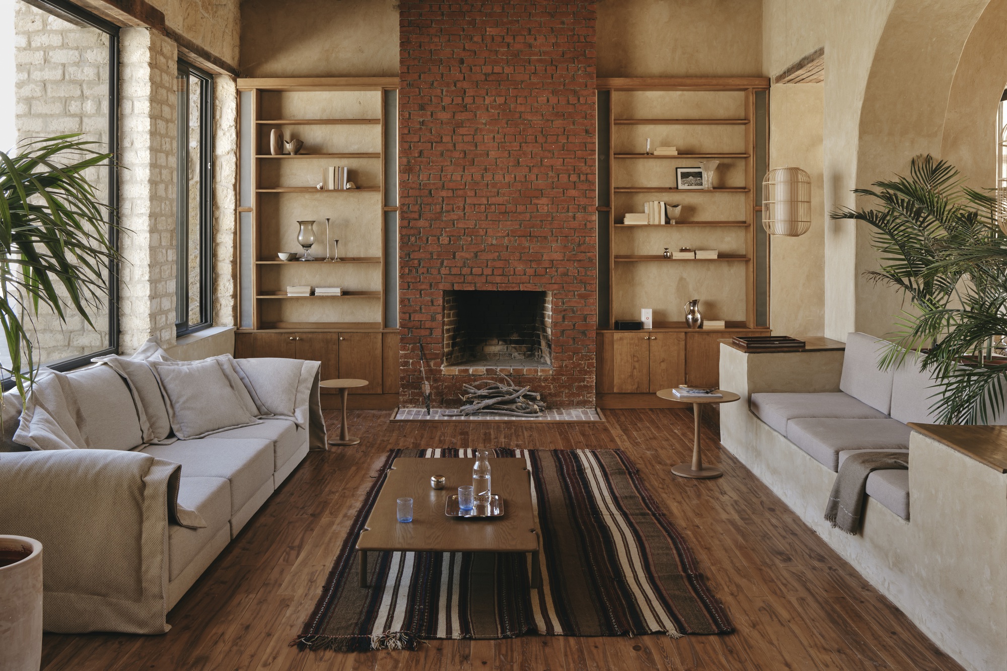 Living room with red brick fireplace flanked by built-in timber shelving
