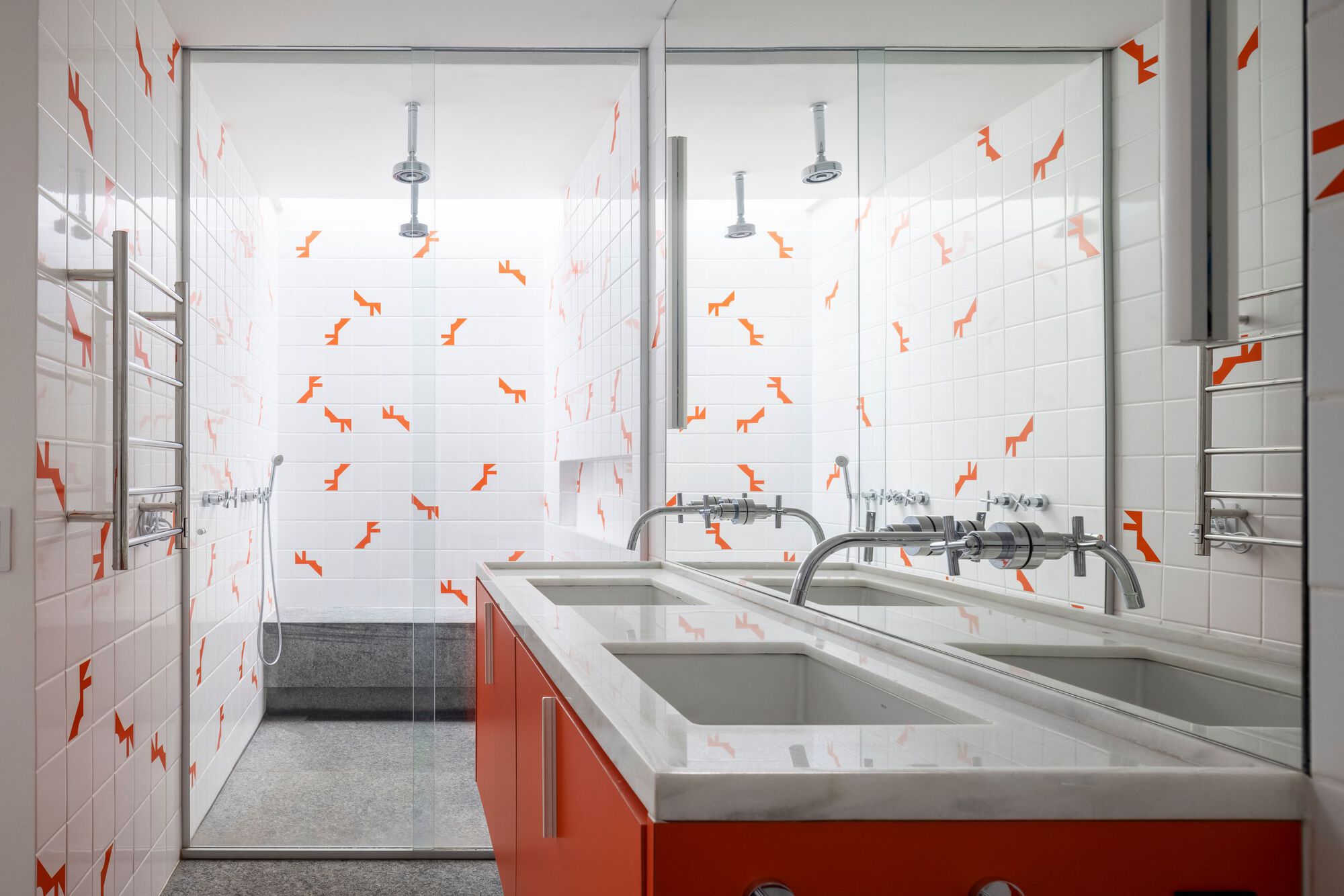 Bathroom vanity with orange cabinetry and white tile walls featuring scattered orange geometric decals
