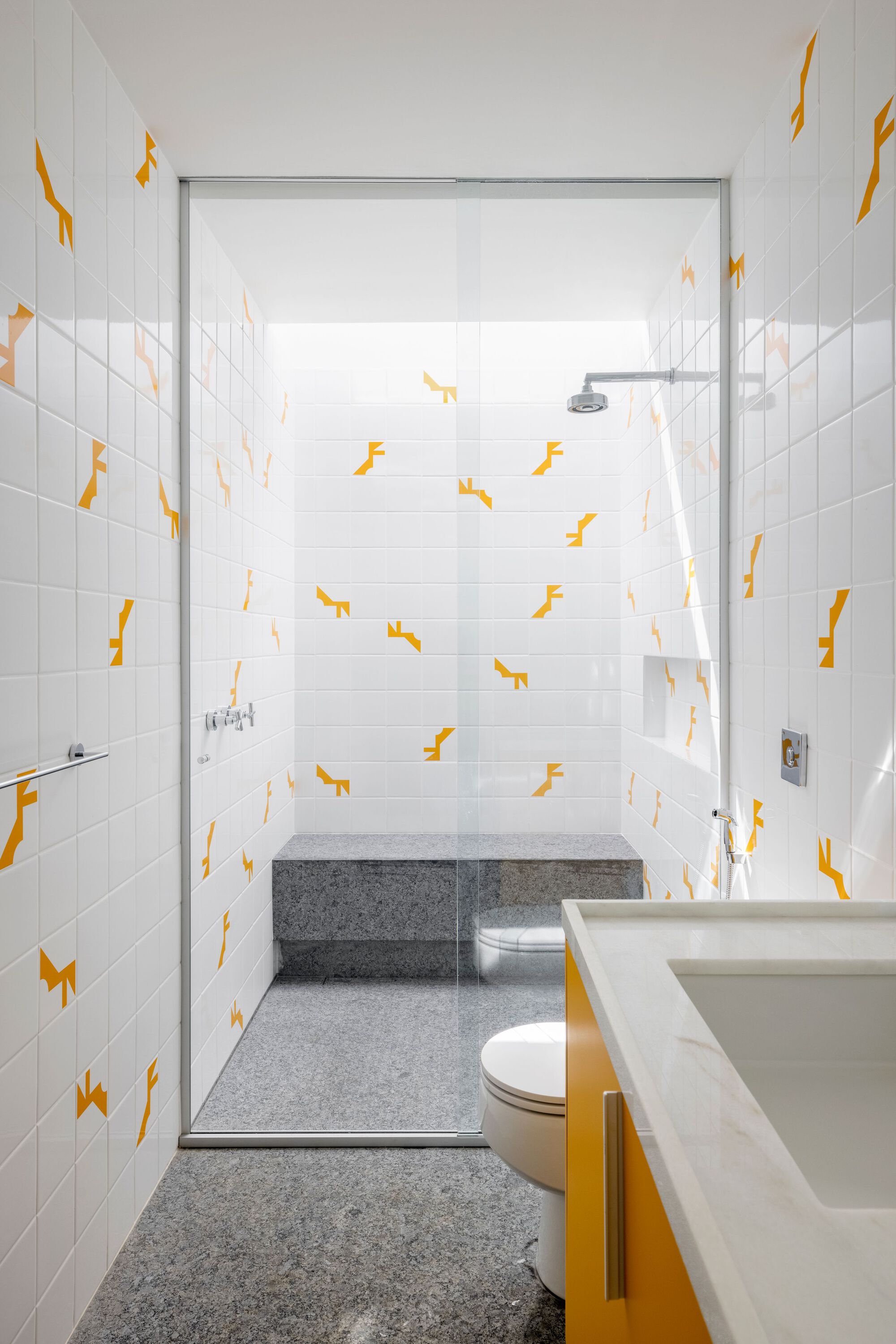 Bathroom with glass shower enclosure, yellow vanity base, and white tiles with yellow animal-shaped decals