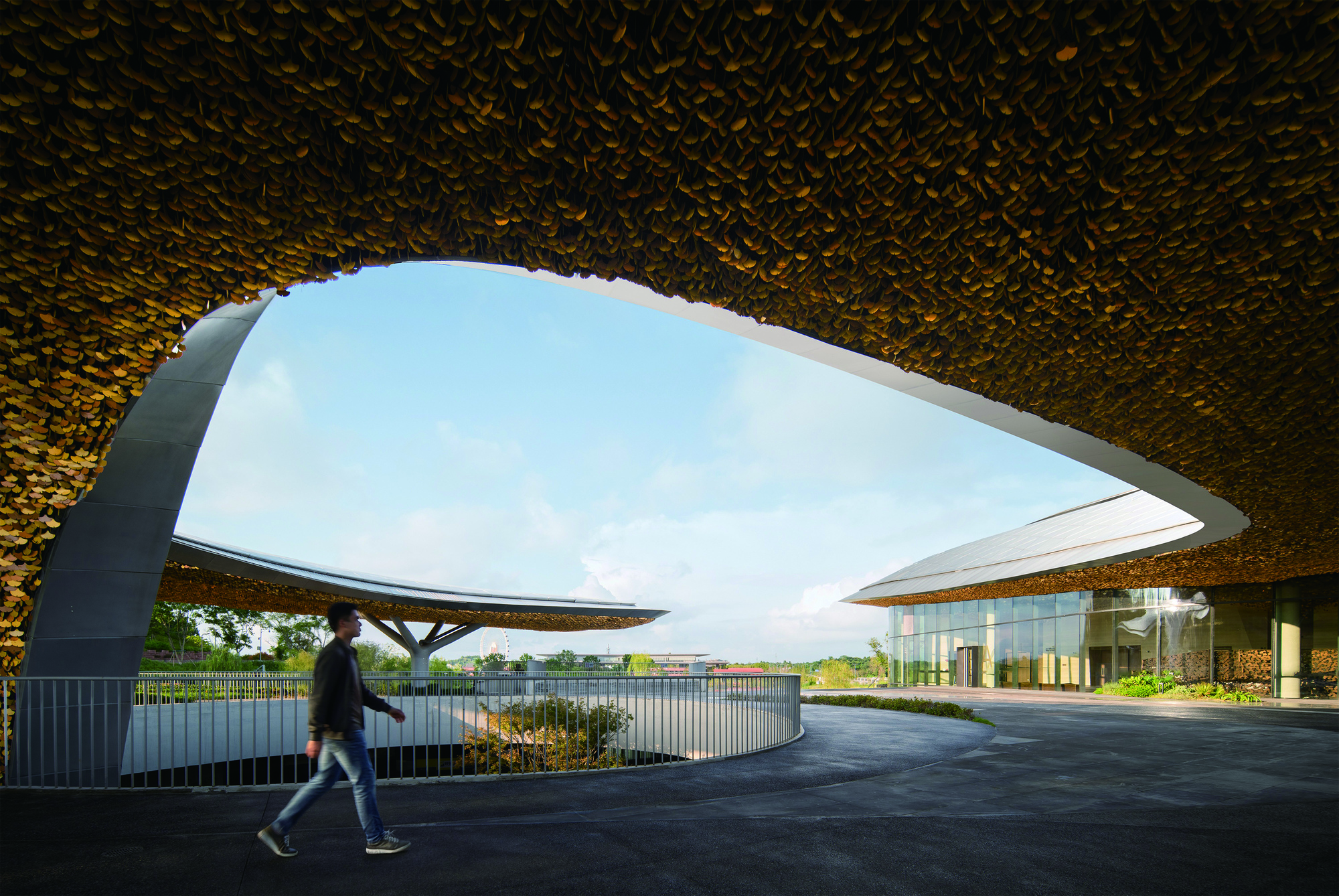 Covered entry drive with a pedestrian passing beneath the sweeping golden textured canopy