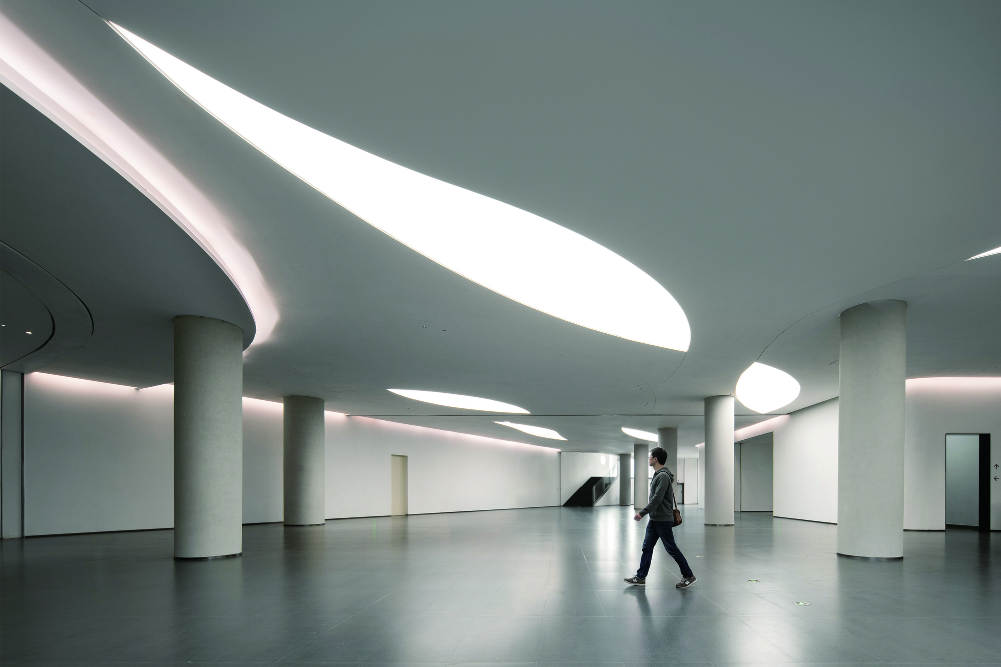 Lobby with curved skylights cutting through the ceiling as a visitor walks across polished floor