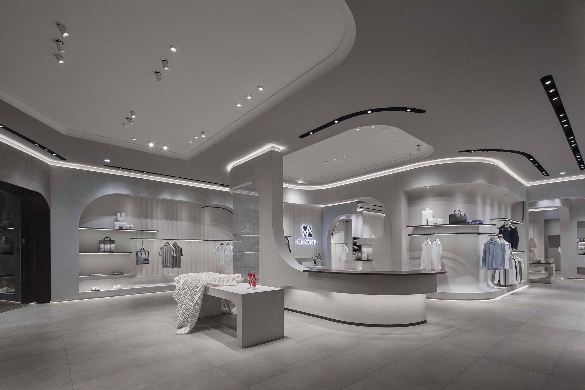 Wide view of the retail interior showing curved ceiling planes with integrated lighting and display alcoves