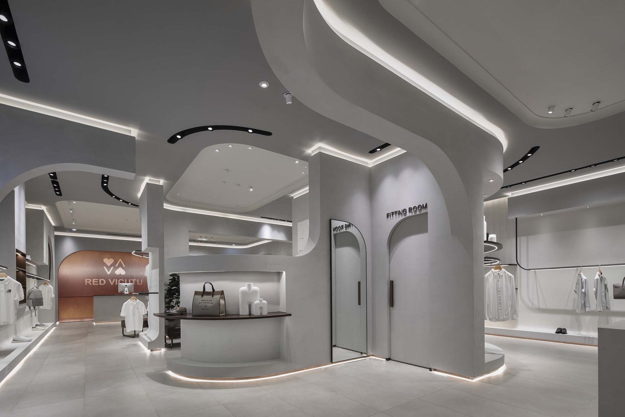 Retail interior with flowing ceiling plane and curved white display volumes under recessed lighting