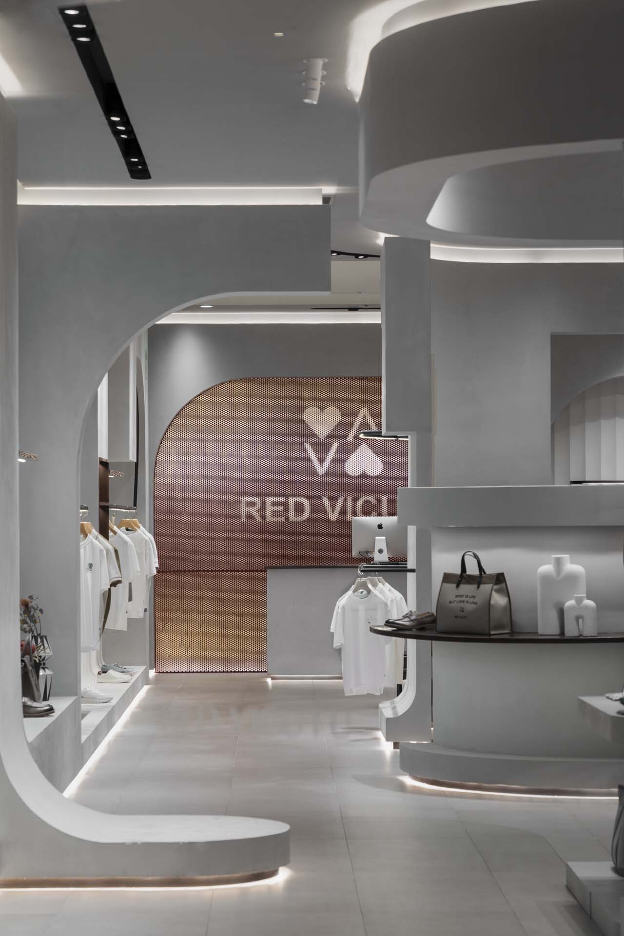 Arched portal with copper mesh screen backdrop connecting retail zones with curved white millwork