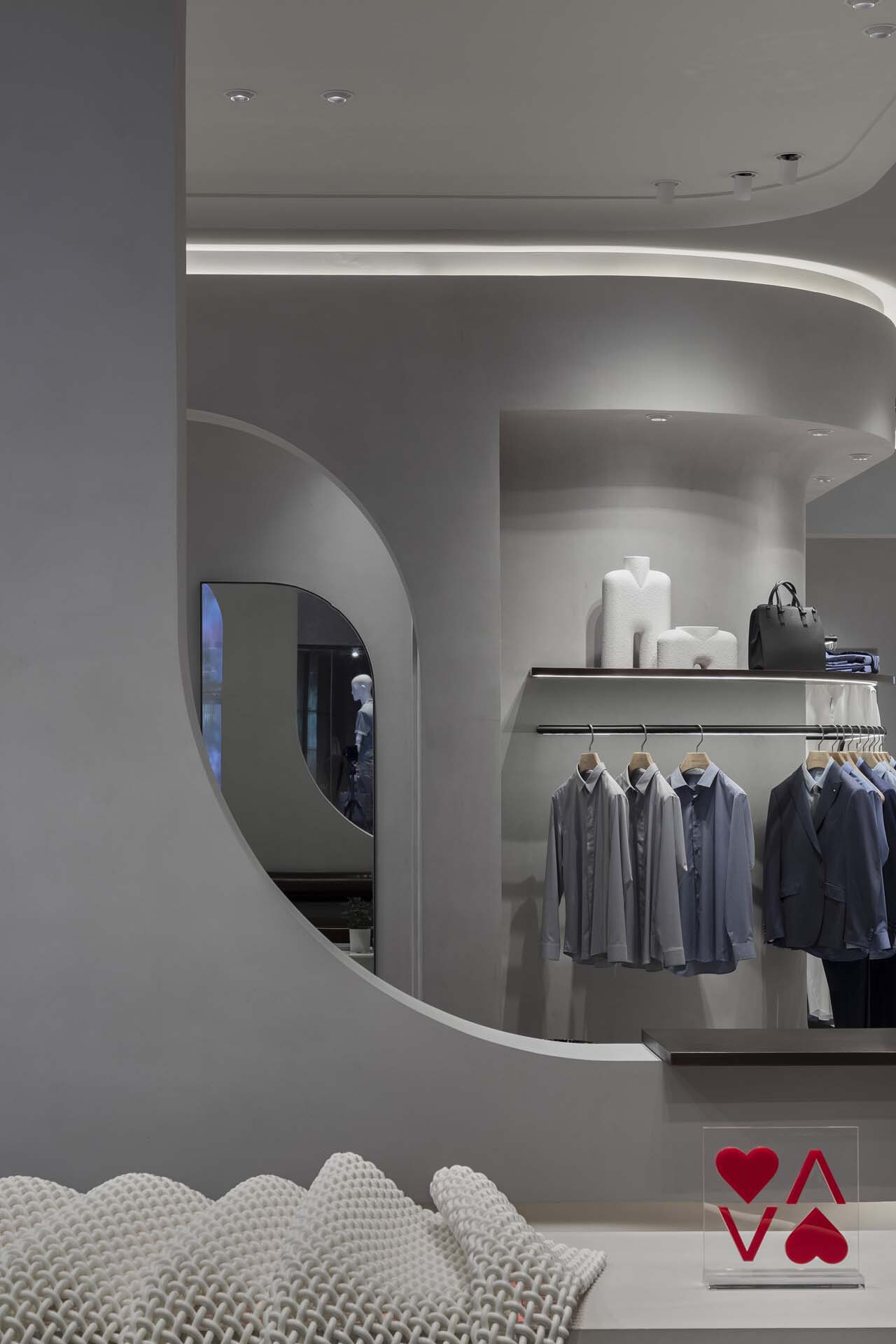 View through curved archway into retail space with recessed cove lighting above rounded walls