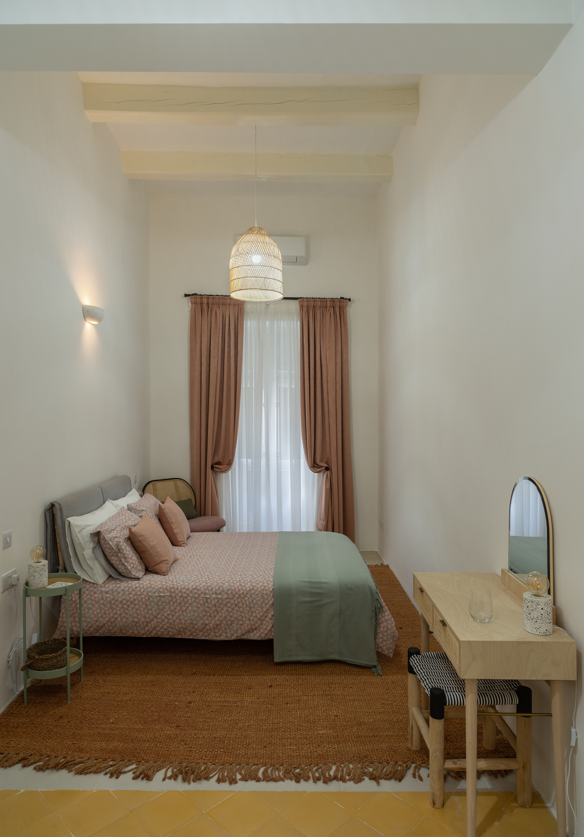 Bedroom with exposed timber ceiling beams and a woven pendant light above the bed