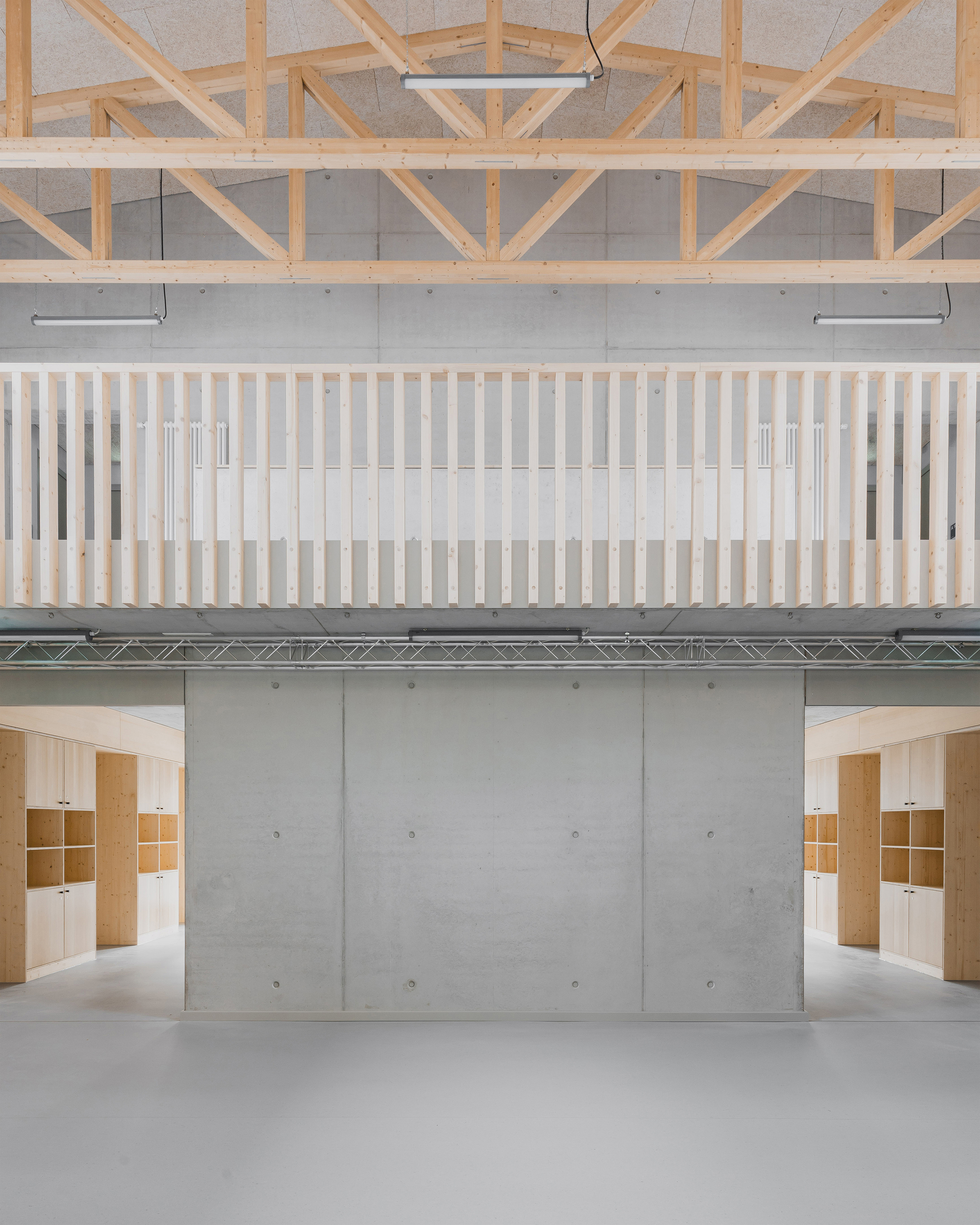 Vertical batten balustrade overlooking concrete wall with plywood shelving units below timber truss ceiling