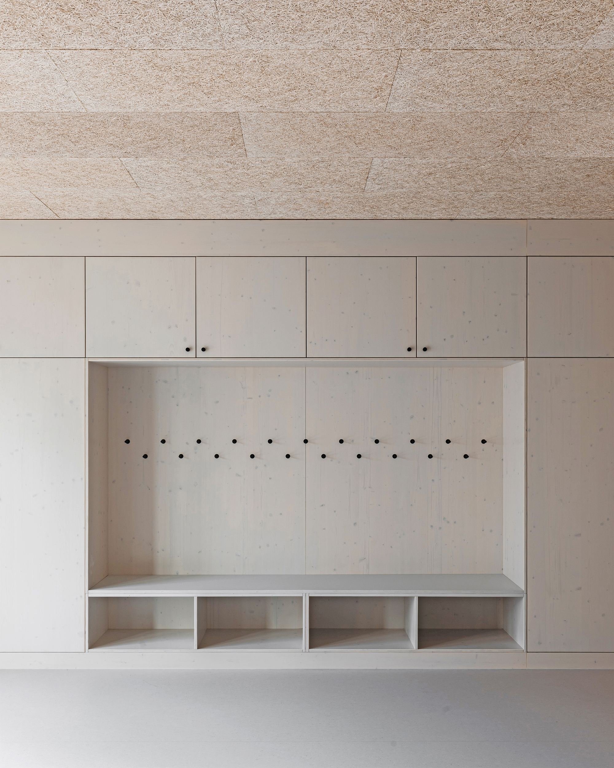 Built-in mudroom alcove with plywood panels, coat hooks, and cubby storage below